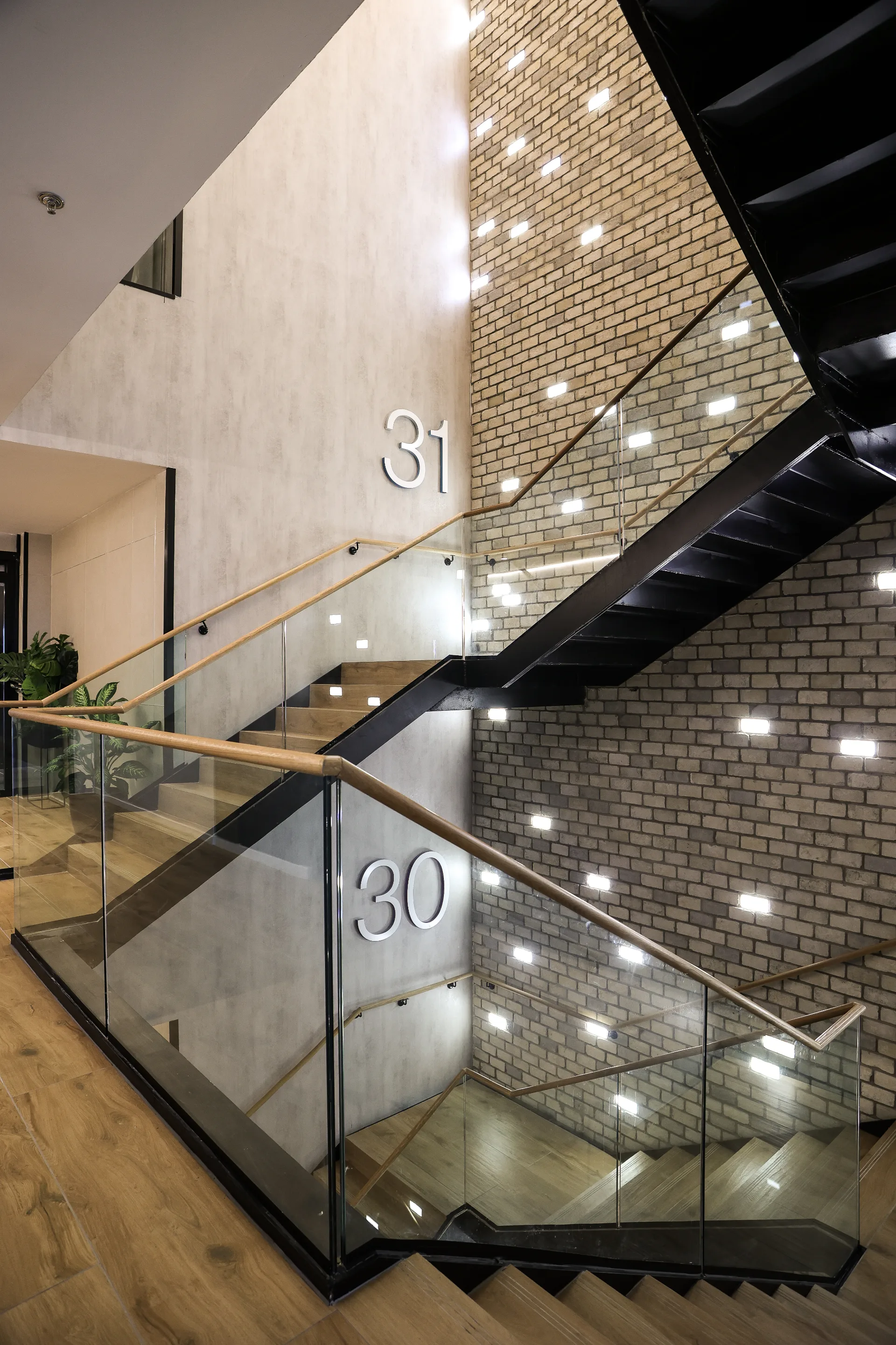 The interior staircase with a downlit brick wall