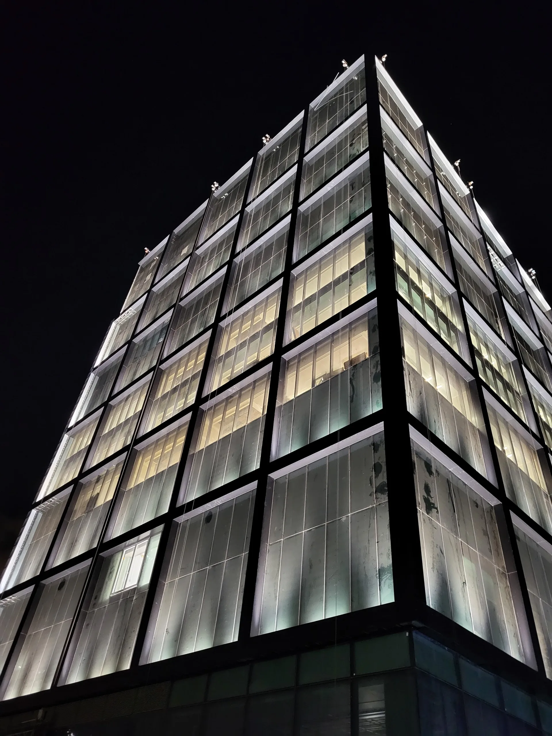 The curtain-wall facade lit at night with floor-edge light