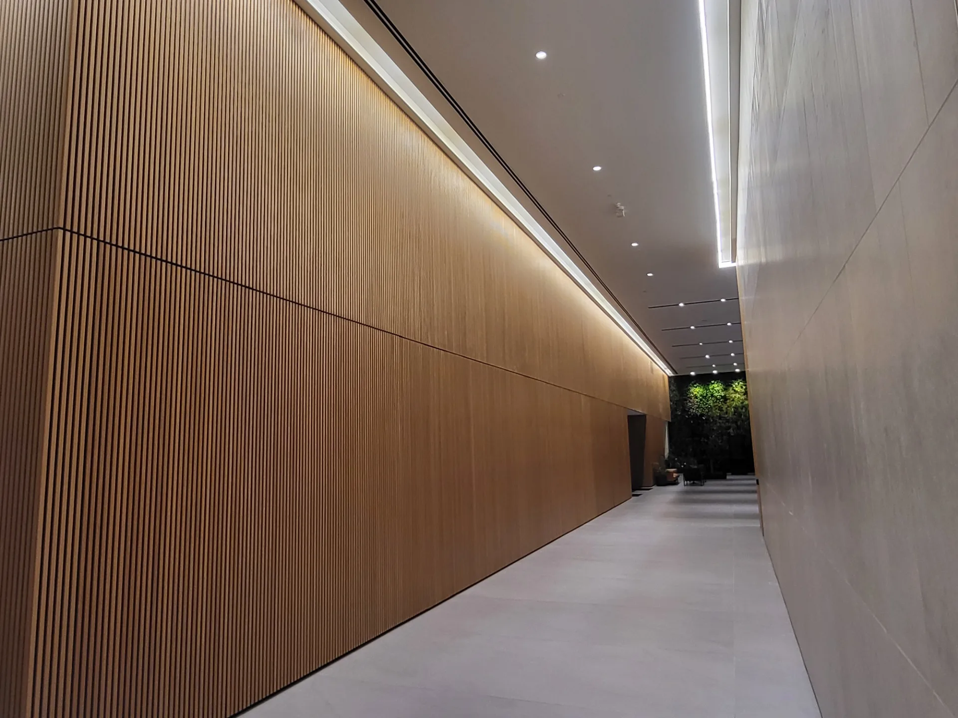 A lobby corridor with a timber-slat wall and cove lighting
