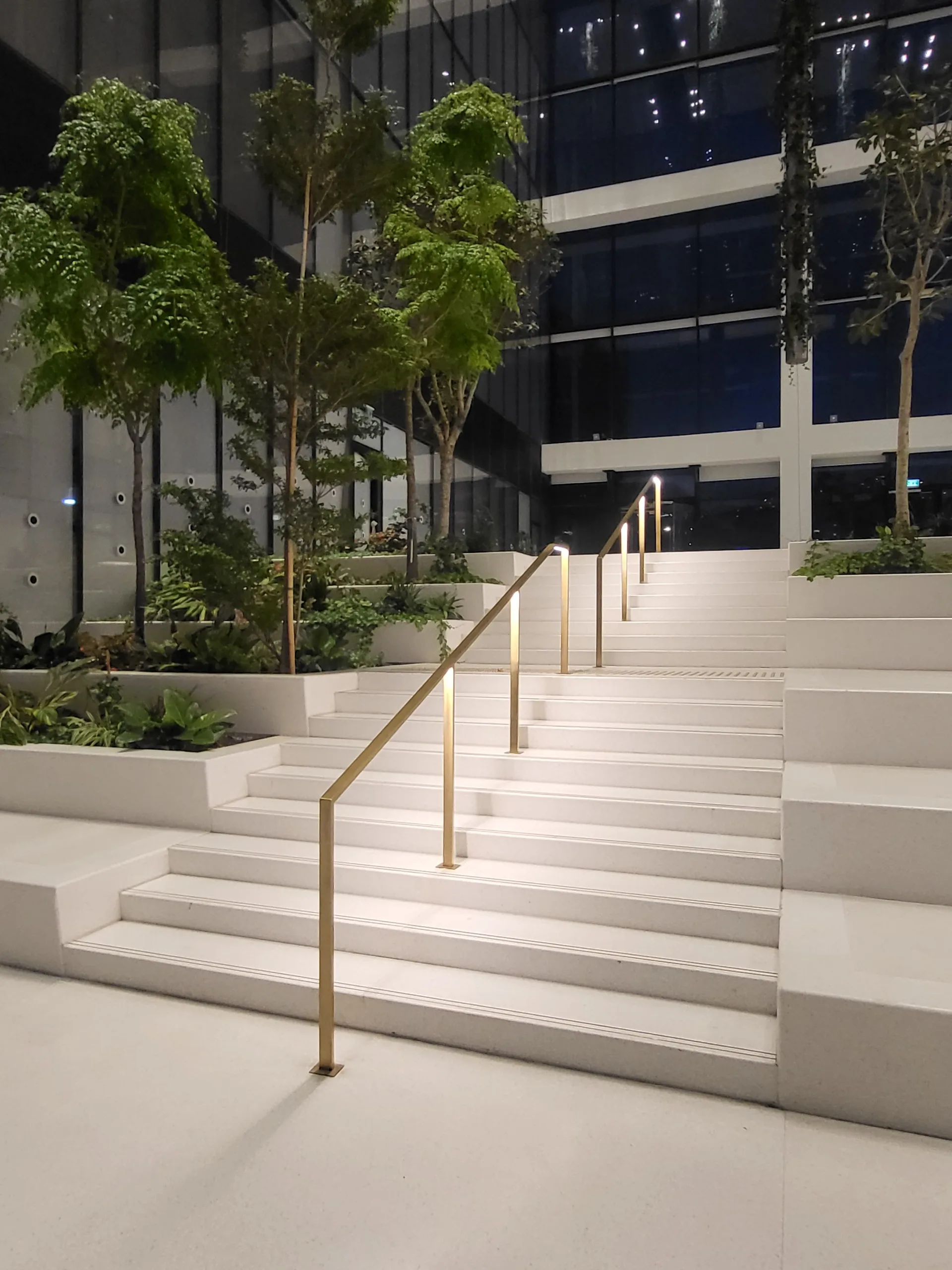 Lit brass handrails on the atrium’s terraced steps