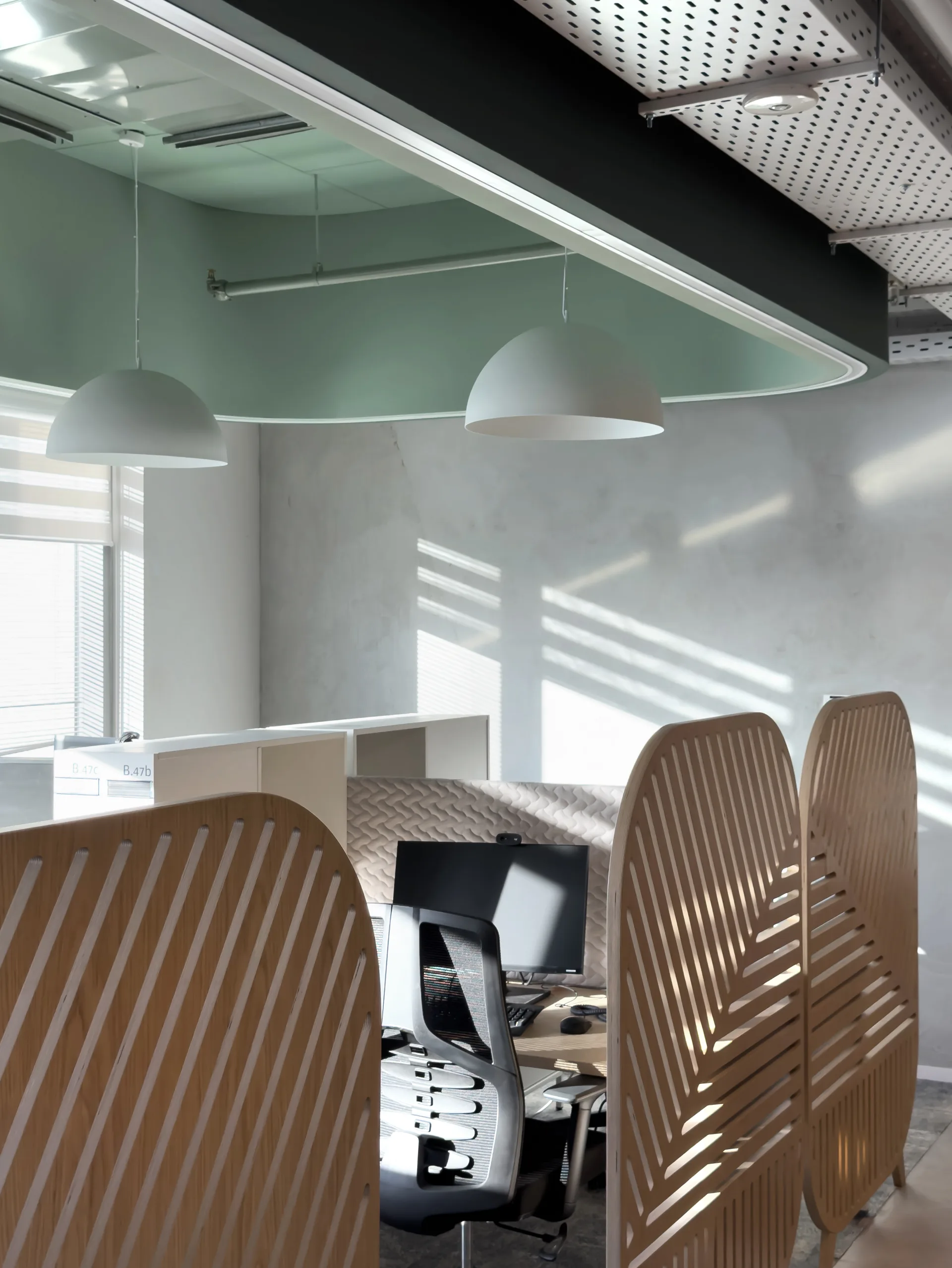 Workstations with timber screens under a green ceiling