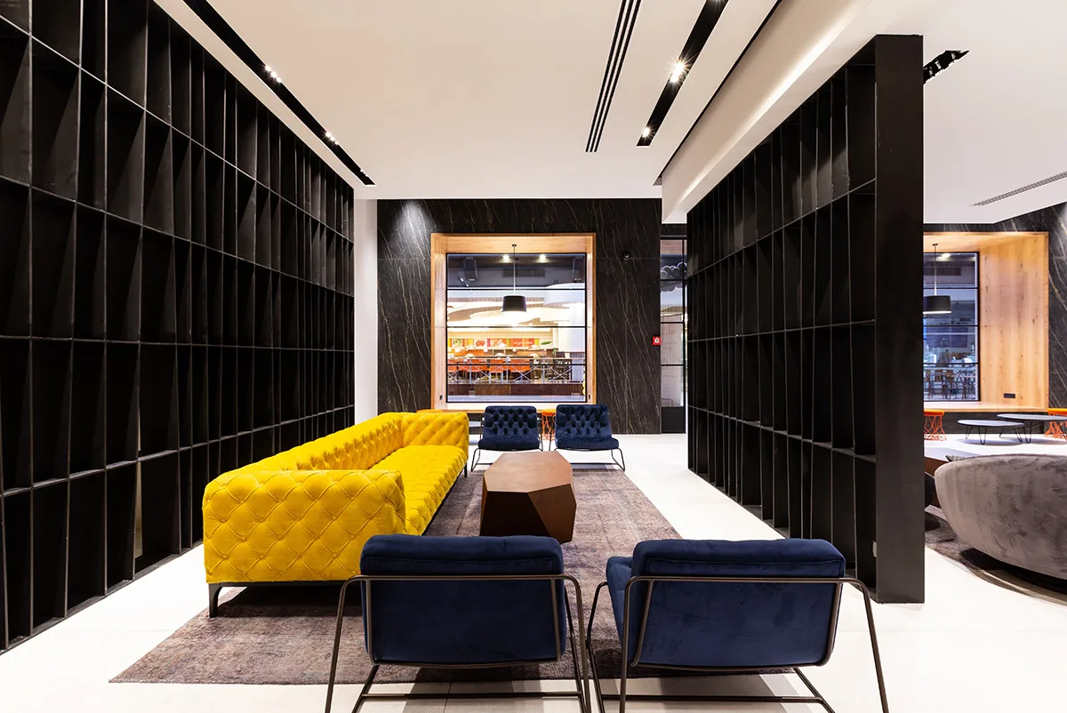 Yellow sofa between black tiled feature walls