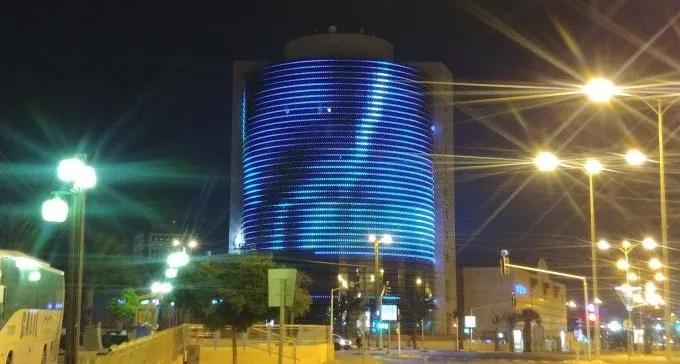 The cylindrical facade lit in blue and cyan LED rings