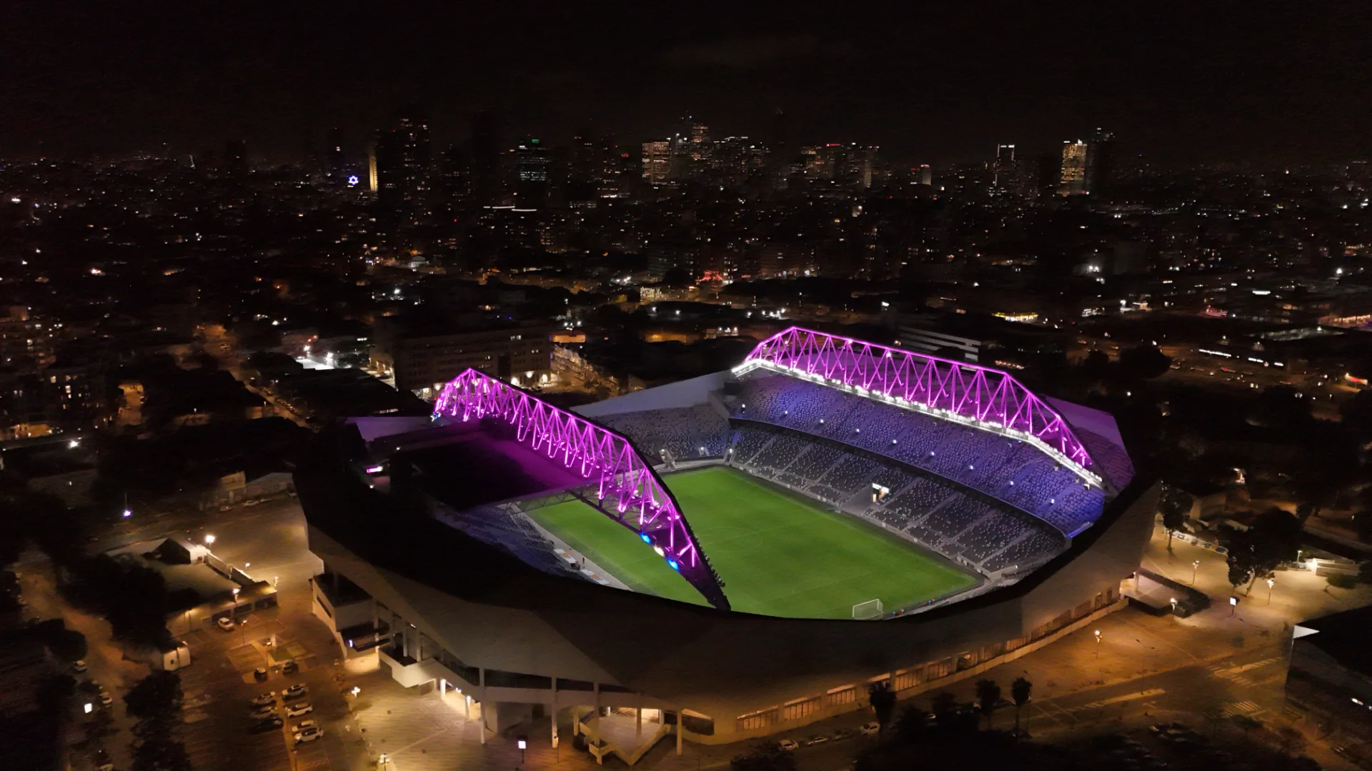 Bloomfield Stadium roof arches lit purple at night