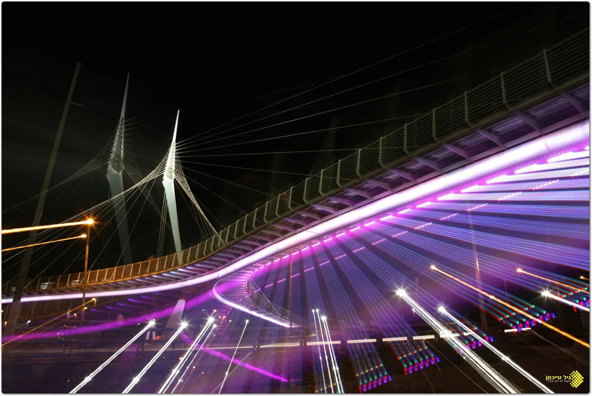 A long-exposure view of the color-lit bridge and light trails