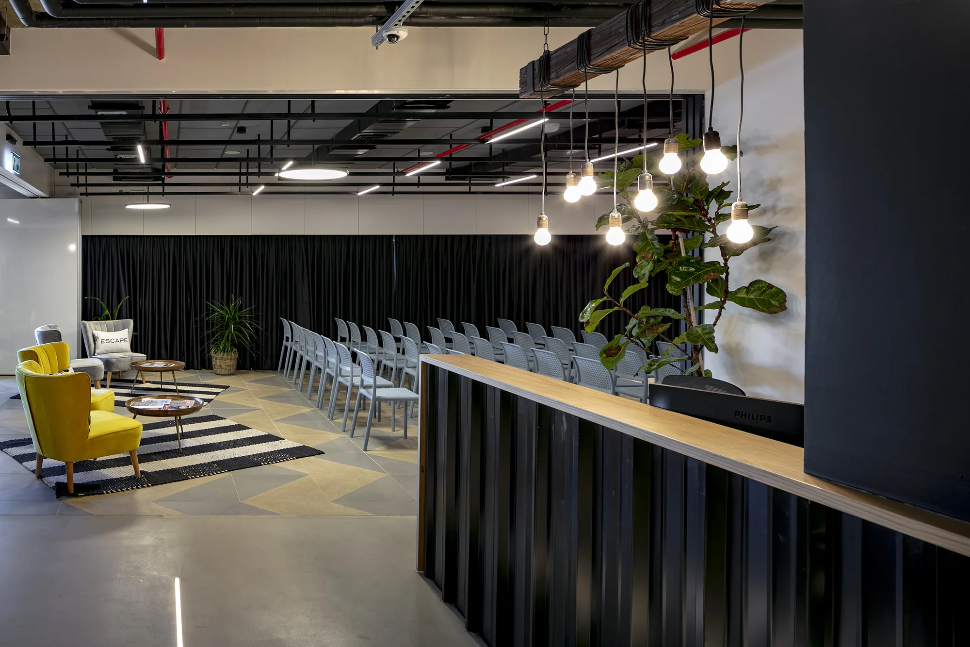 The event space with a reception bar and bulb-cluster lighting