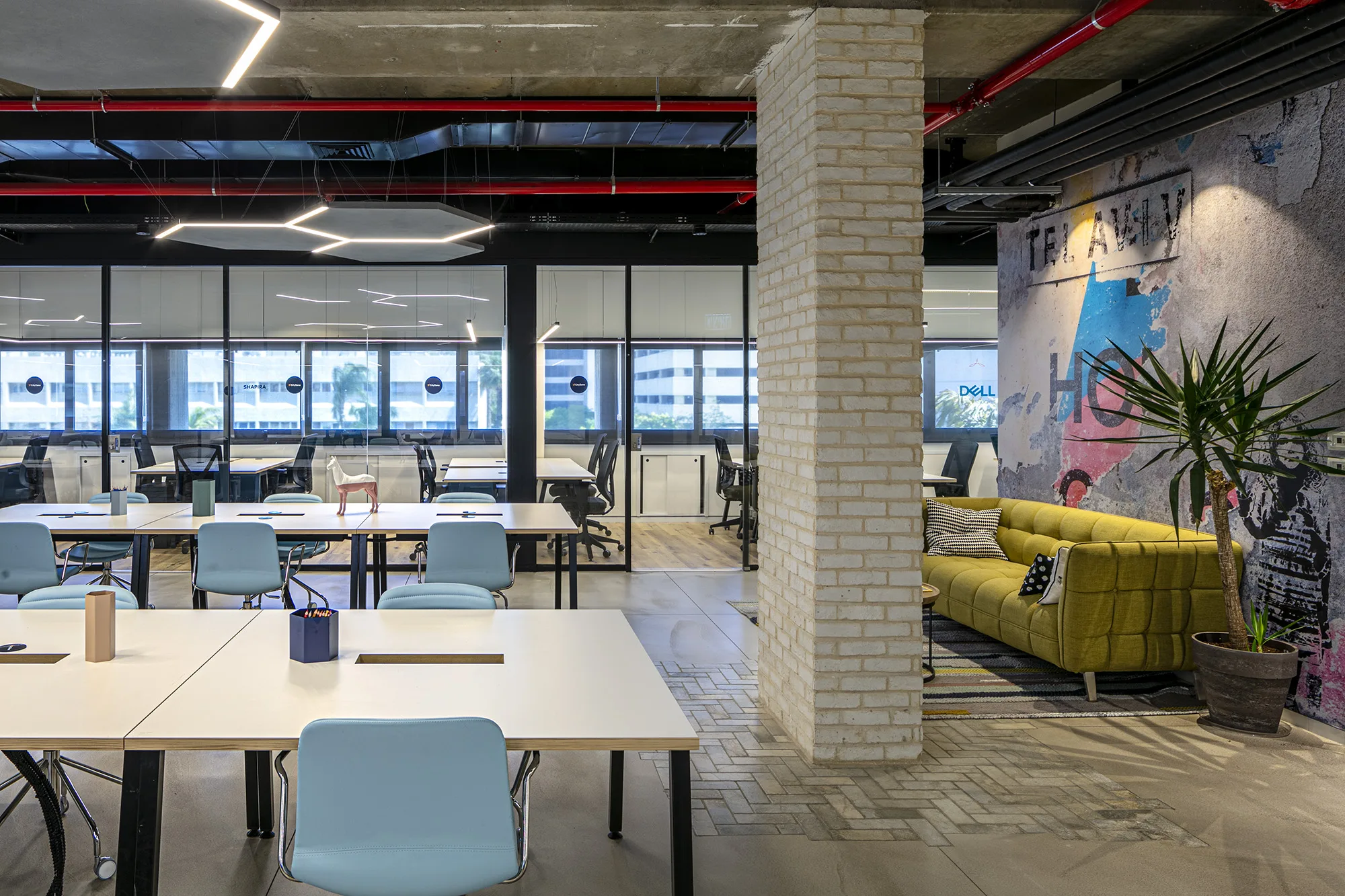 The co-working floor with linear pendants and a Tel Aviv Hub mural
