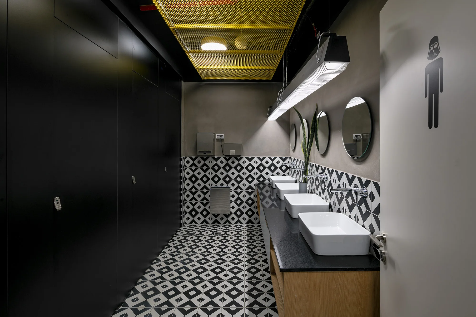 A patterned-tile restroom with a decorative linear pendant