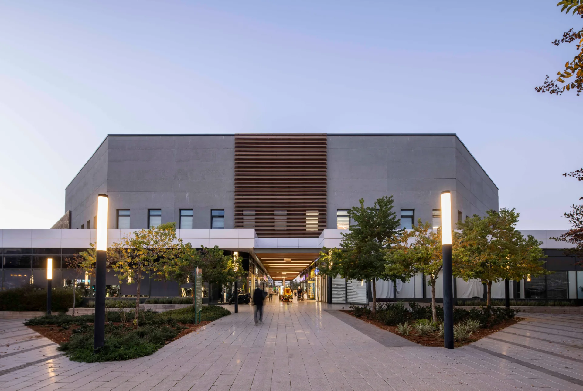 Facade with lit columns along the landscaped plaza
