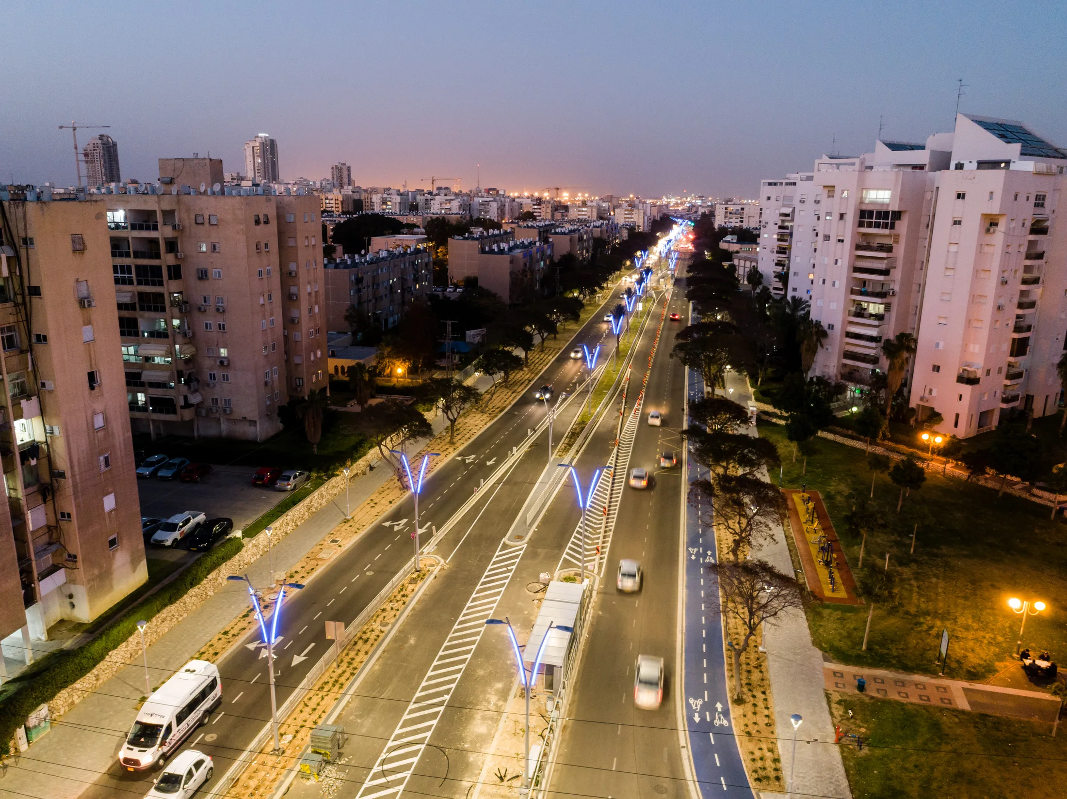 An aerial view of the boulevard with blue-lit poles at twilight