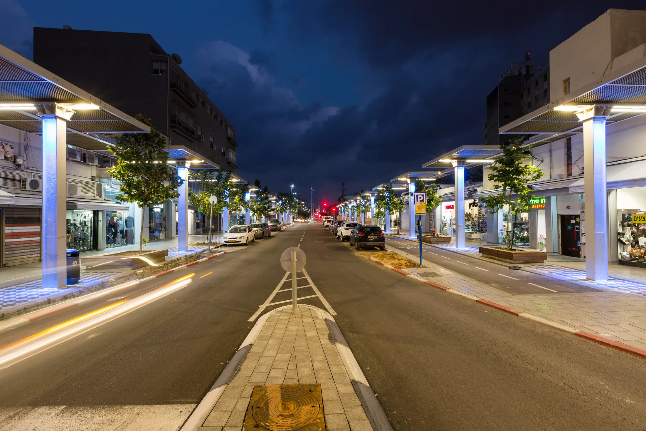 The colonnade street with lit poles at dusk