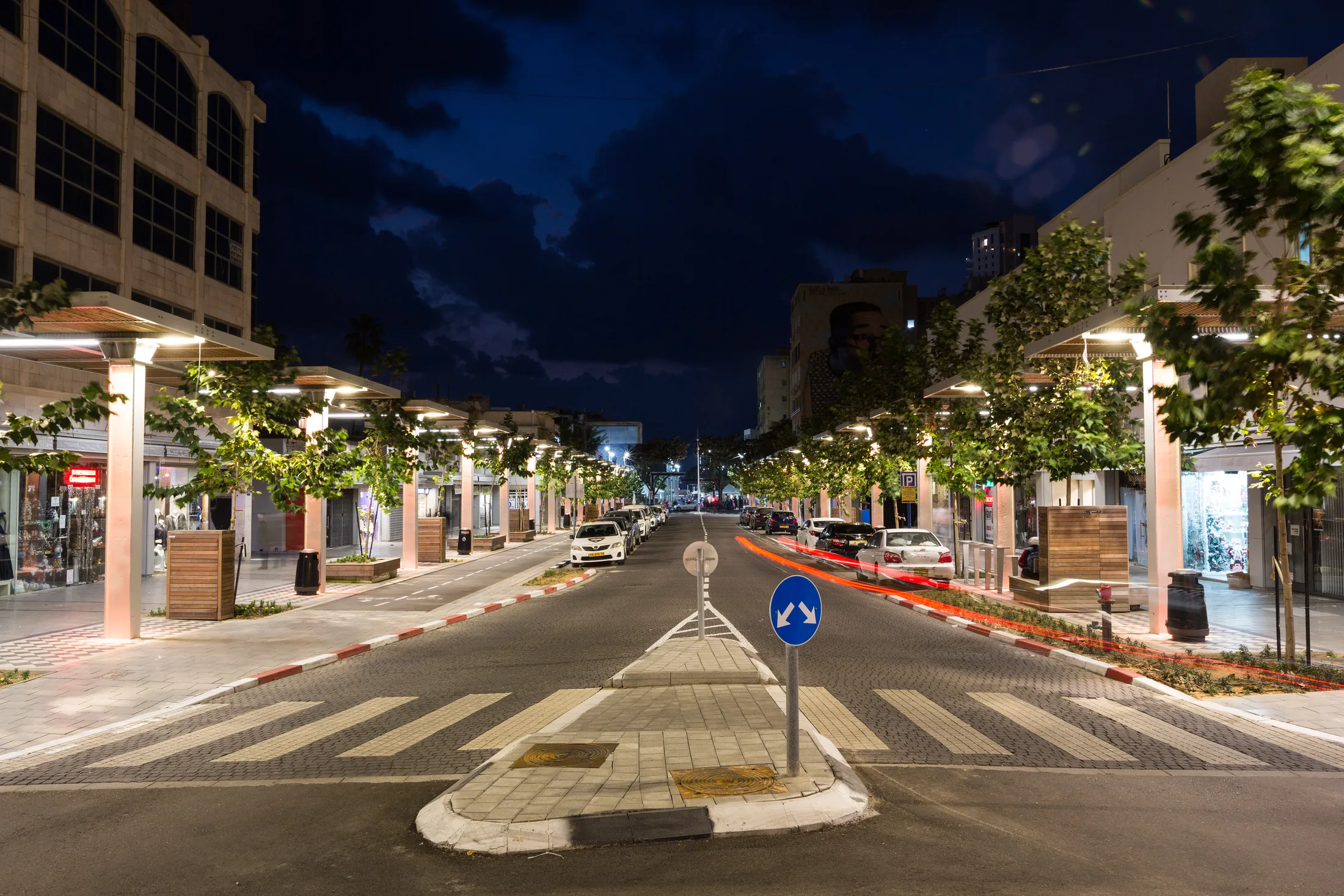 A wide view of the street with a lit median and palms