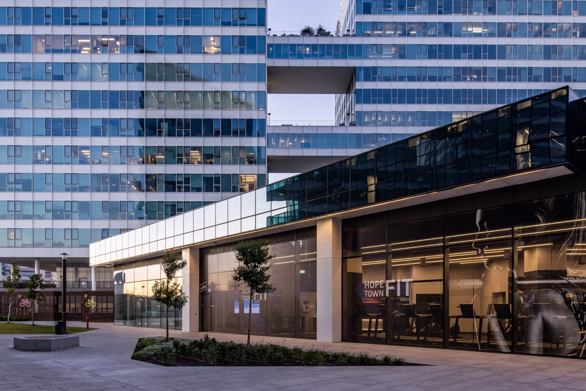 The mixed-use complex and landscaped plaza at dusk