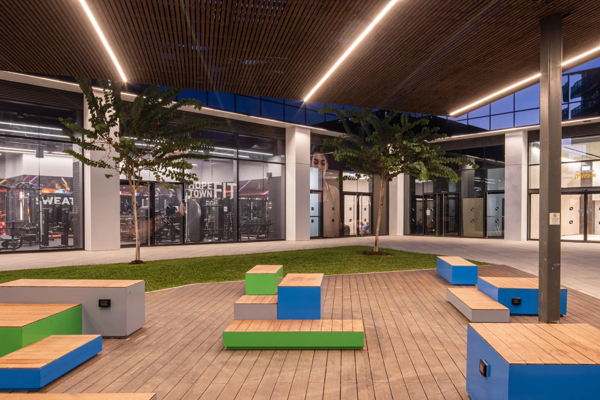Public courtyard with seating and pergola at night