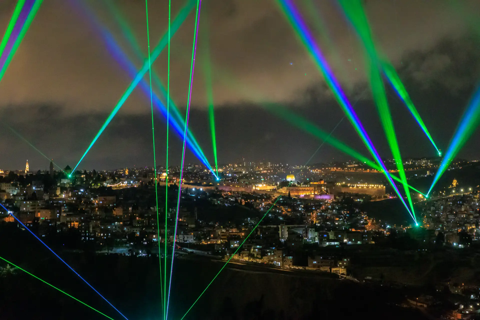 Green and purple laser beams crossing above the Old City