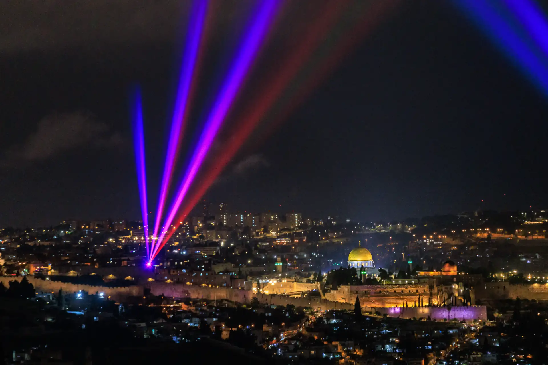 Blue and pink laser beams converging over the Old City of Jerusalem