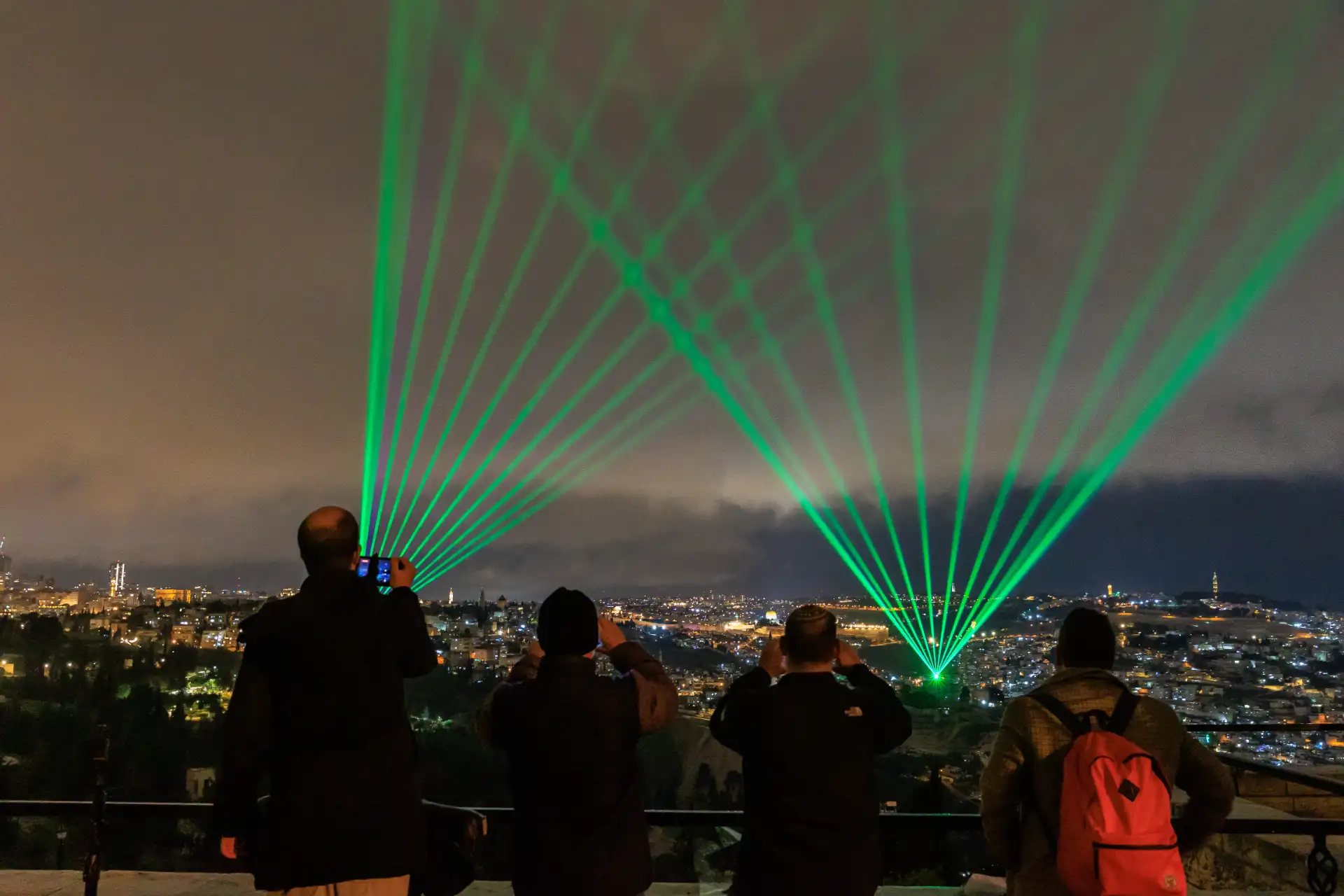 Spectators watching green laser fans from the Armon HaNatziv promenade