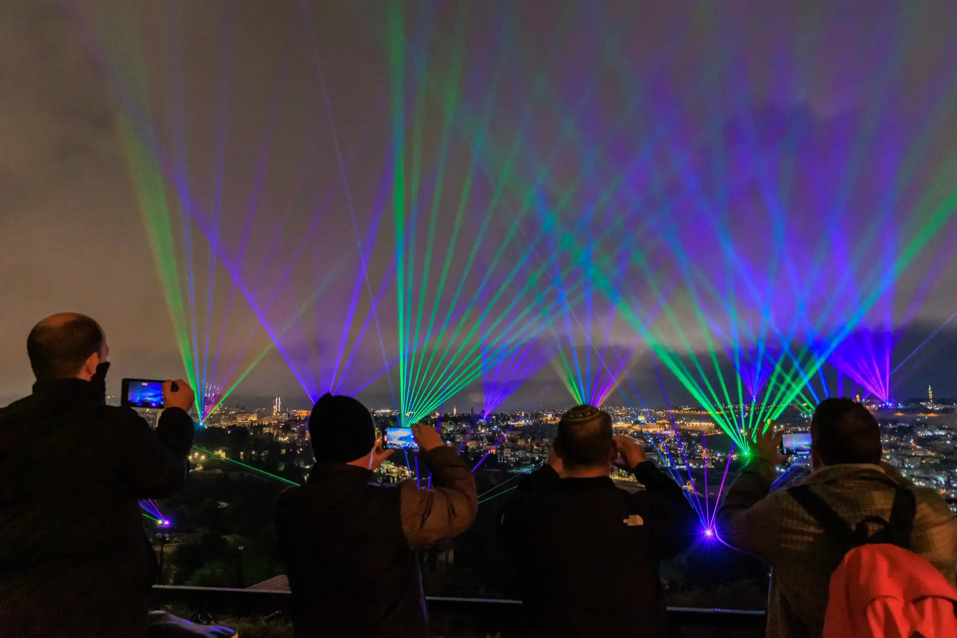 Visitors photographing the multicolored laser show over the city