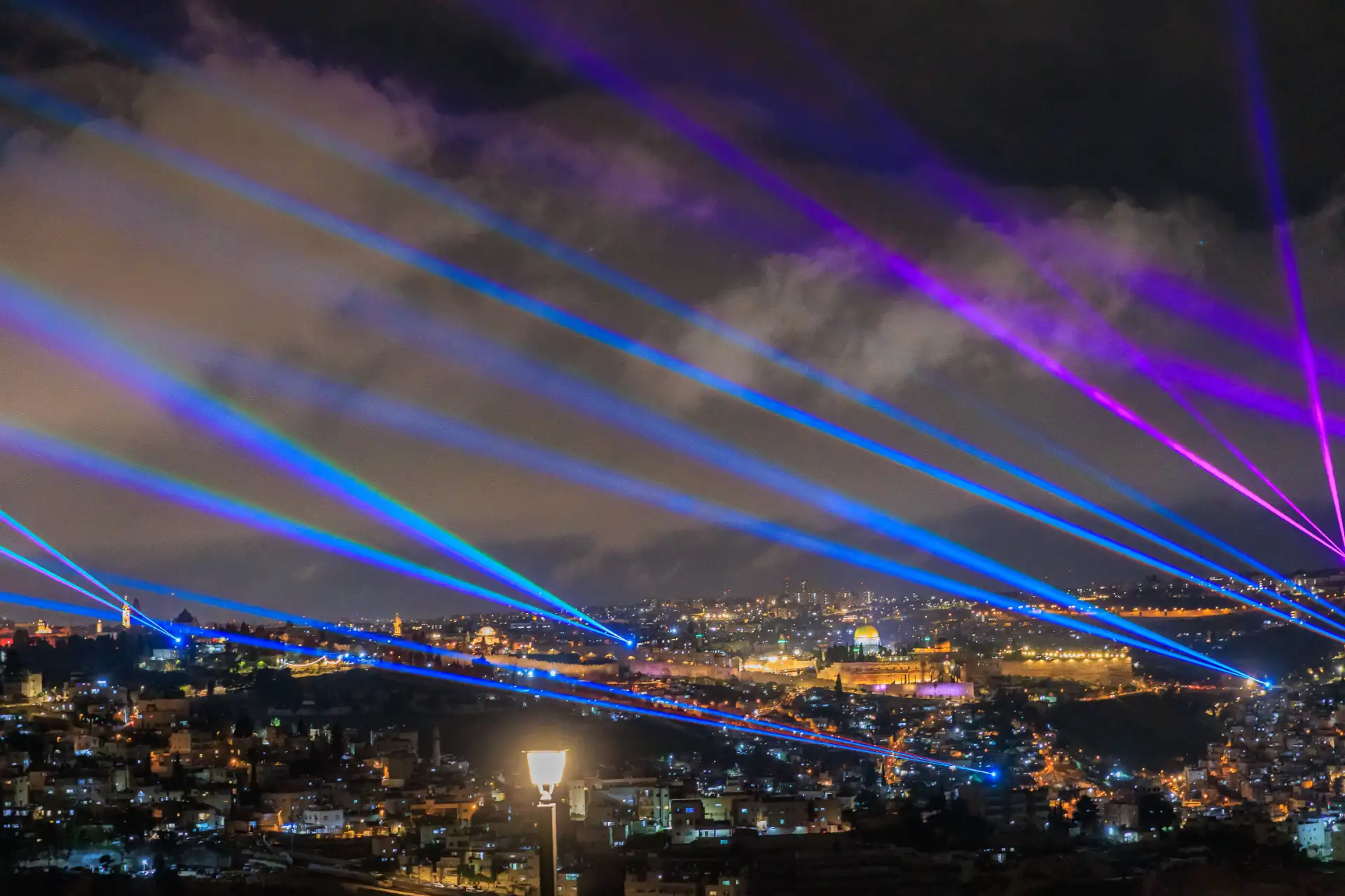 Blue and purple laser beams sweeping across the night sky over Jerusalem