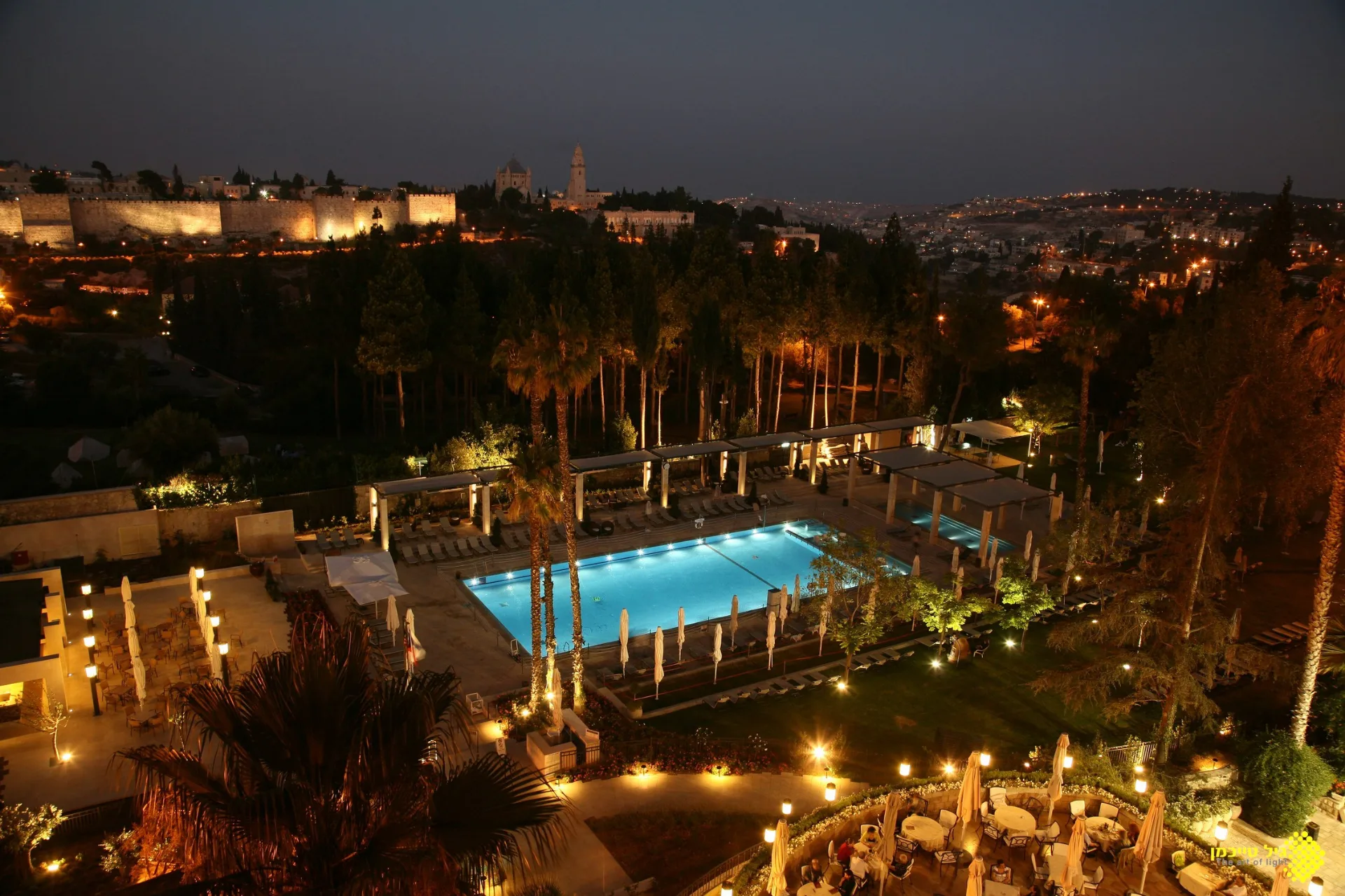 Hotel gardens and pool at night with the Old City walls behind