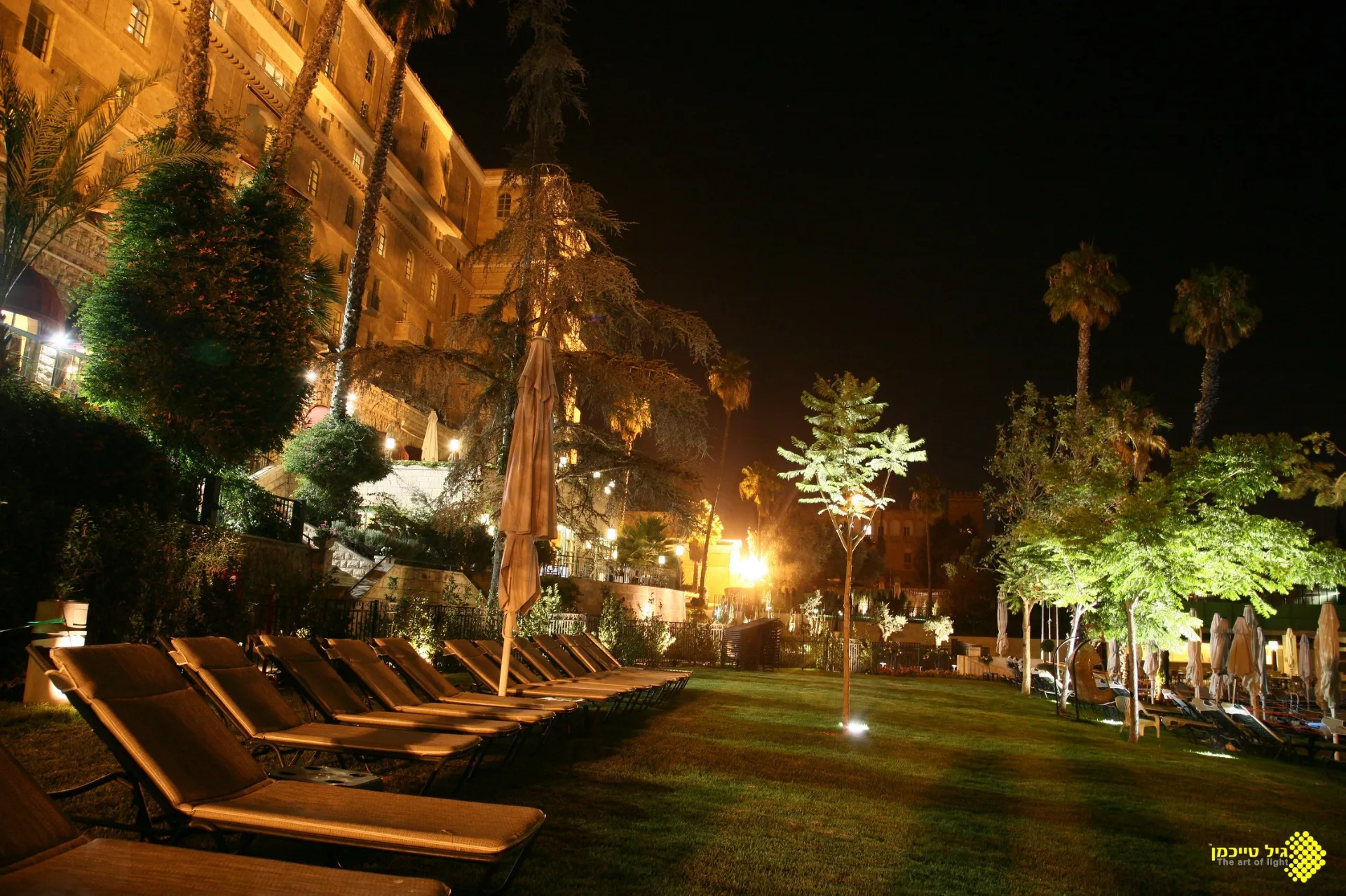 Uplit palms and gardens beside the hotel