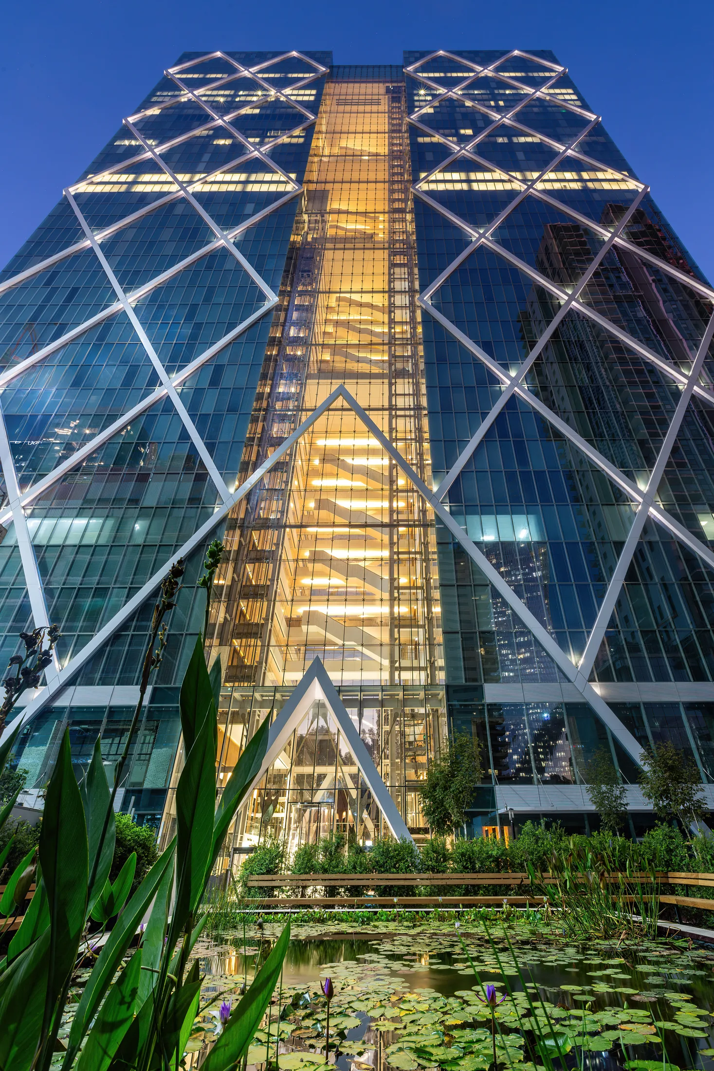 The diamond double-skin glass facade glowing warm in an upward view