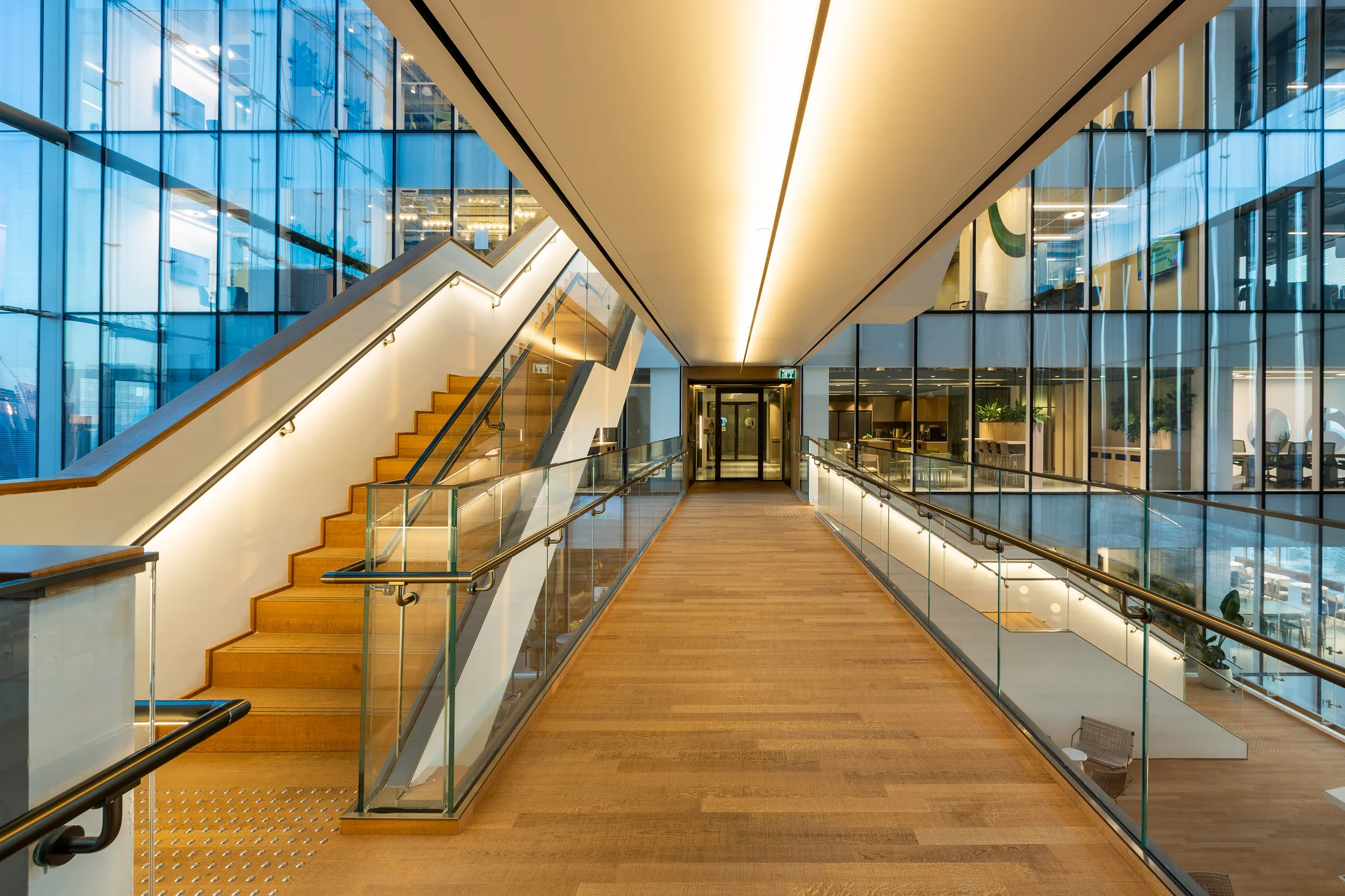 Stairs and a bridge in the atrium with cove lighting in the wood