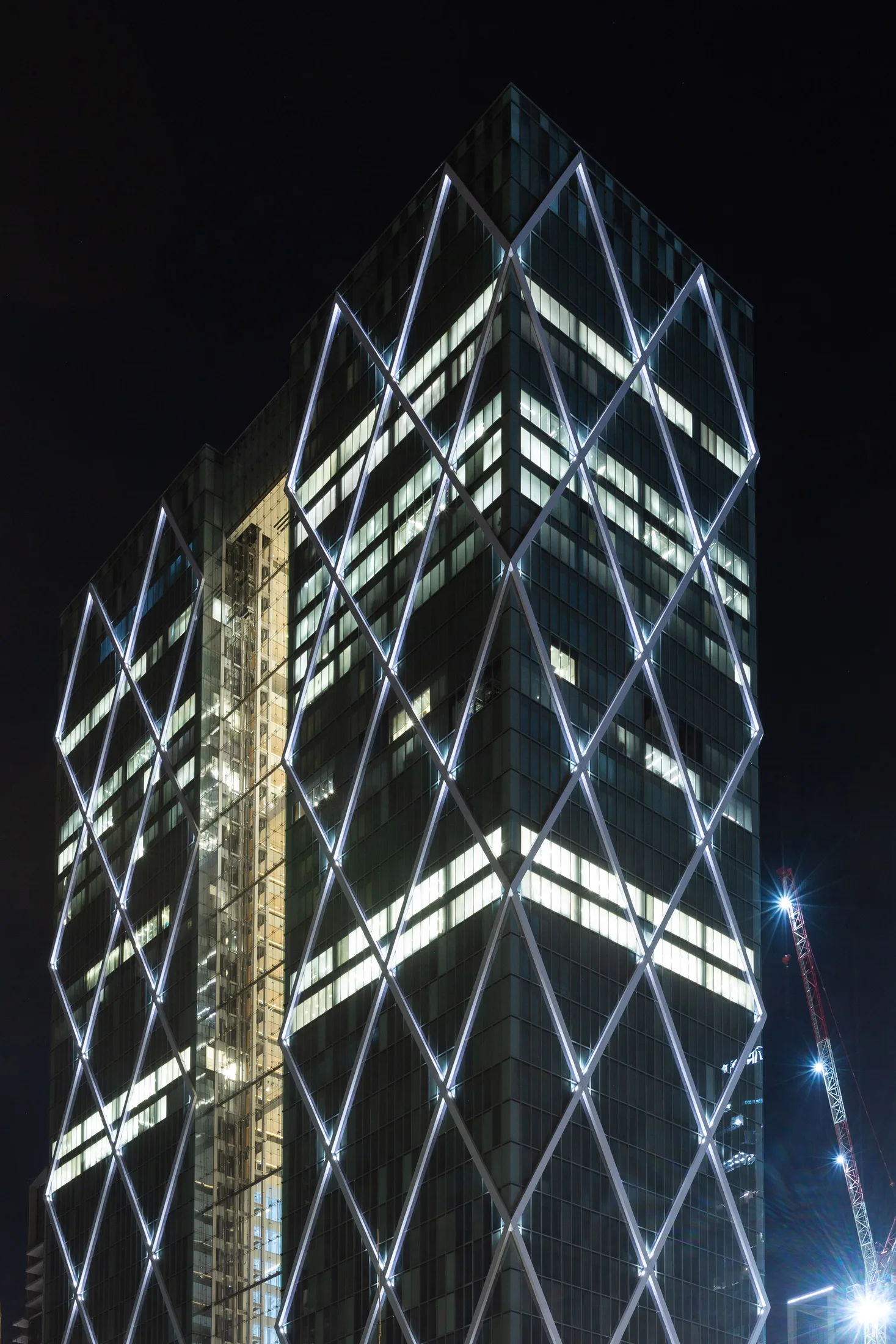 A glowing triangular glass element in the facade at night