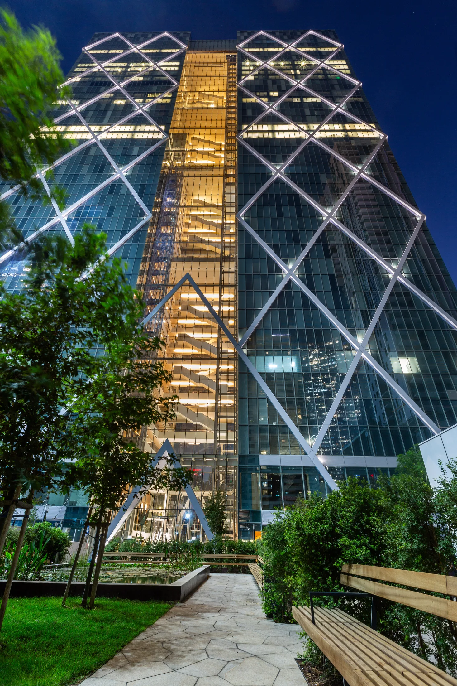 The tower facade with a tree and planting in front at dusk
