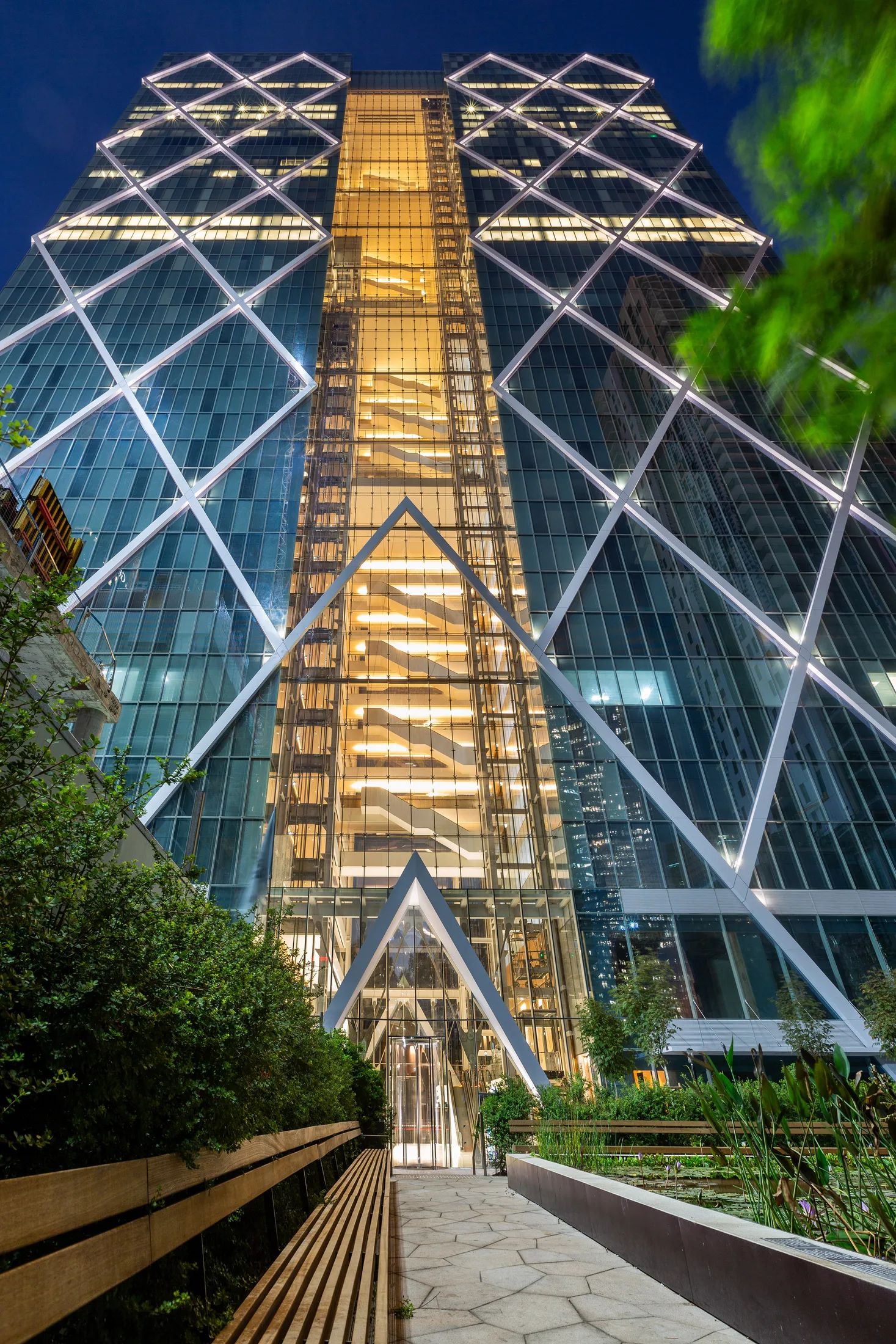 The diamond-patterned tower facade at dusk with trees in front