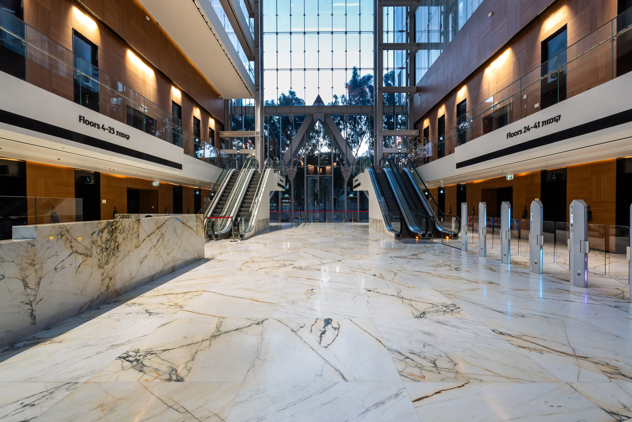 A marble lobby with escalators and warm recessed lighting