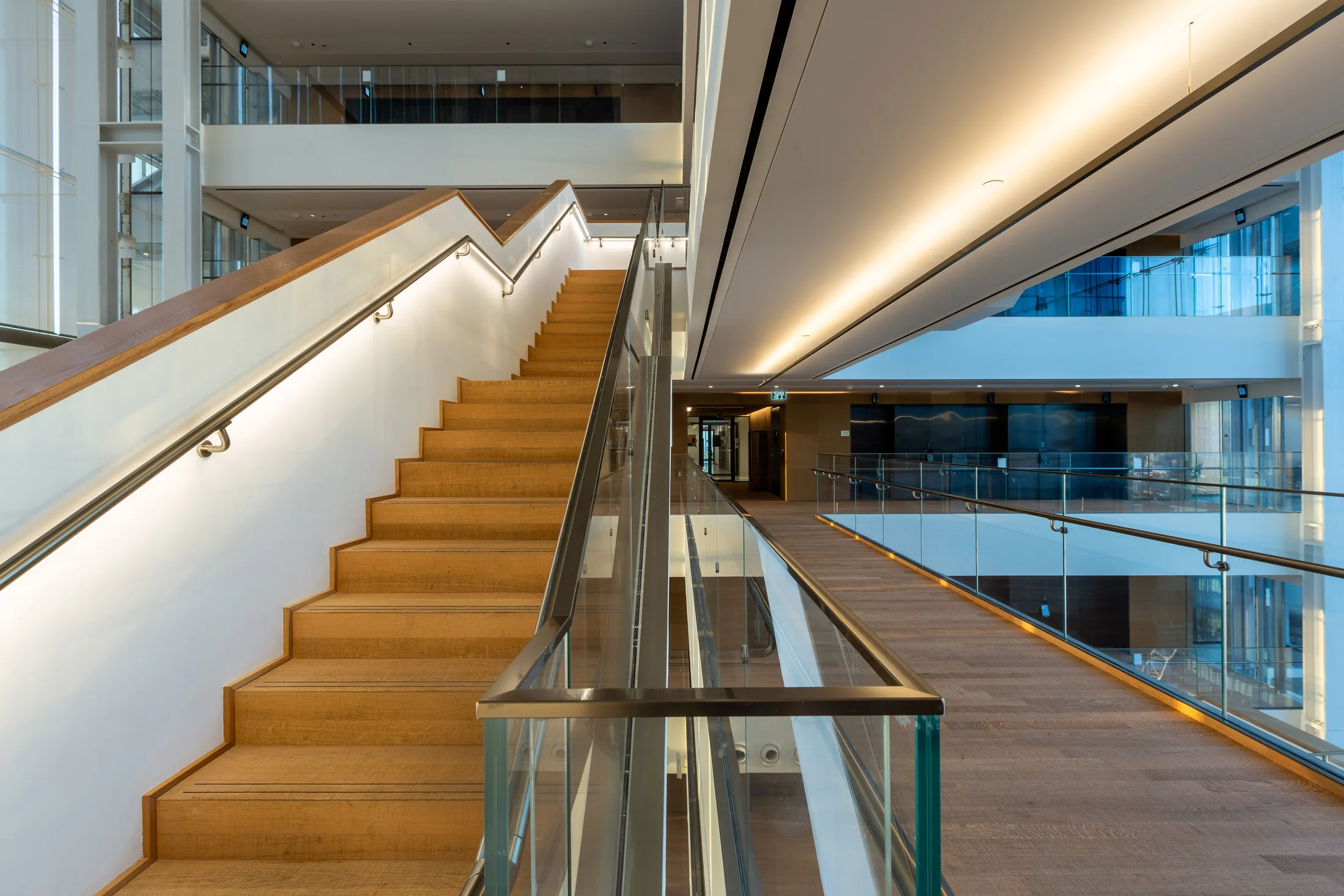 Floating stairs in the atrium with wood cladding and cove lighting