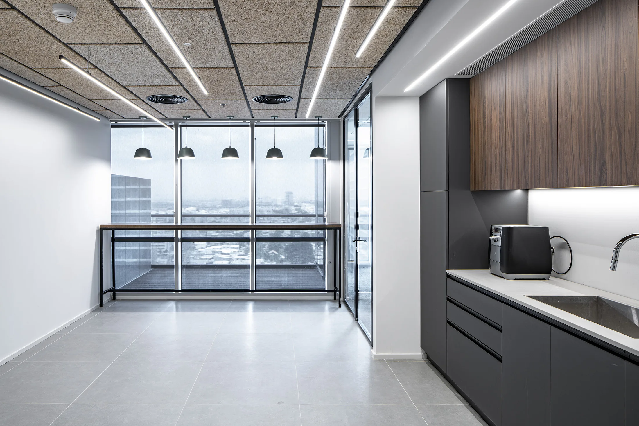 A kitchenette with black pendant lights and under-cabinet lighting