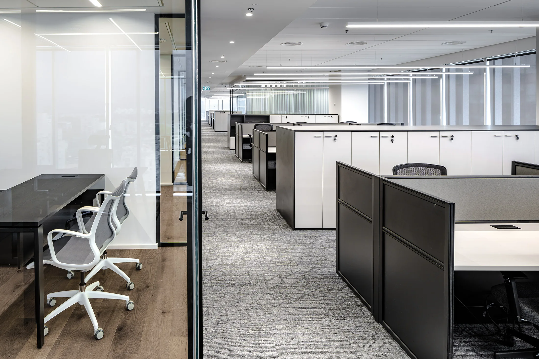 An open-plan workspace with linear light lines and a private office