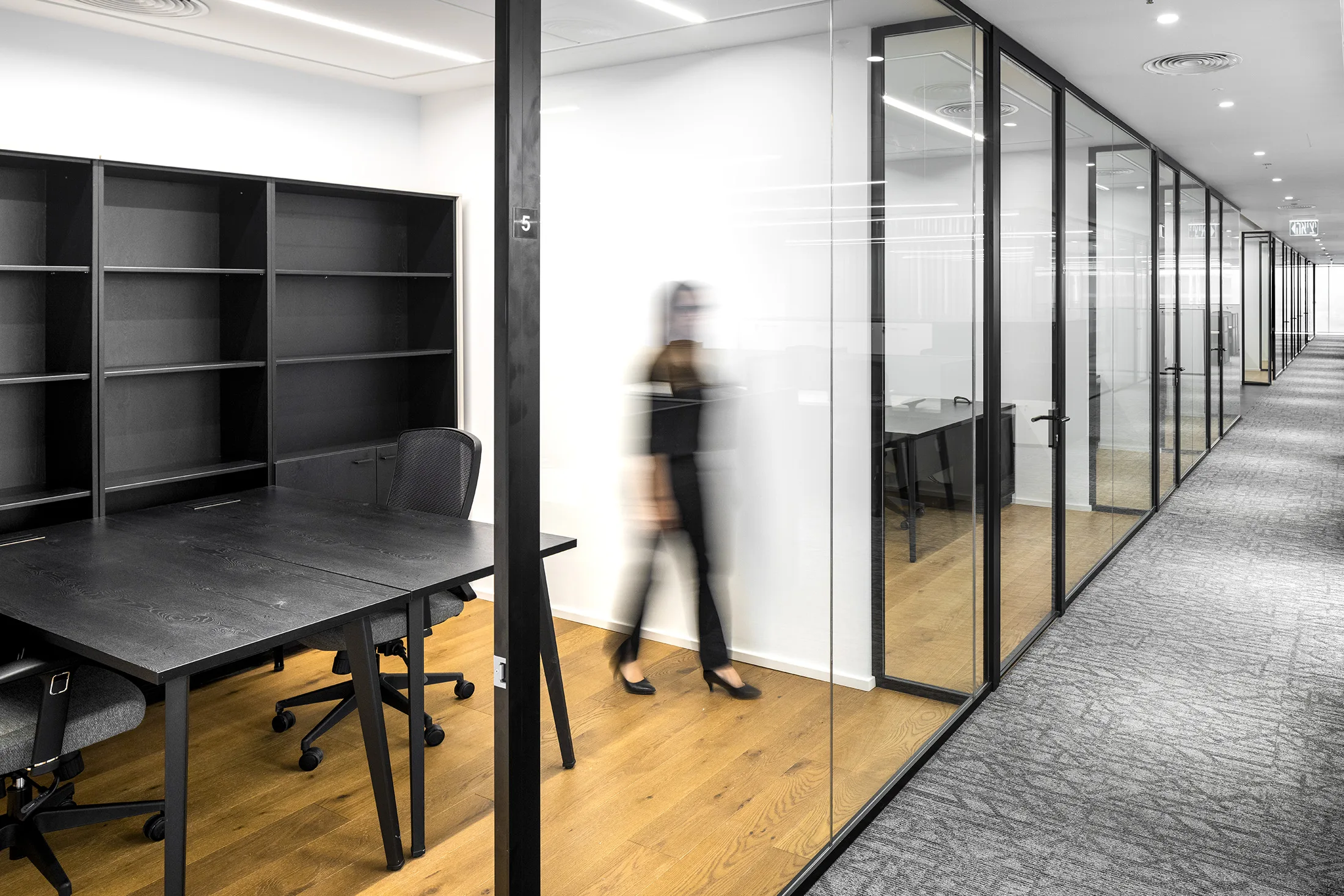 A work-and-storage area with a wood floor beside a glass partition