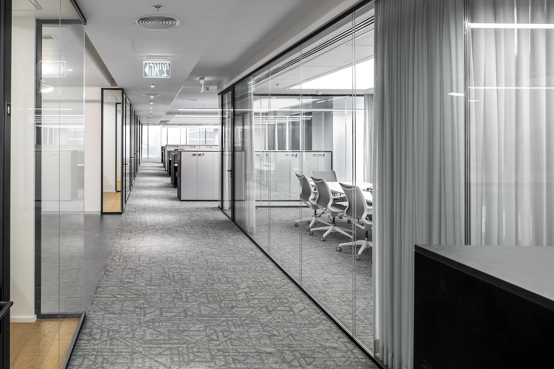 A corridor beside a meeting room behind a glass partition