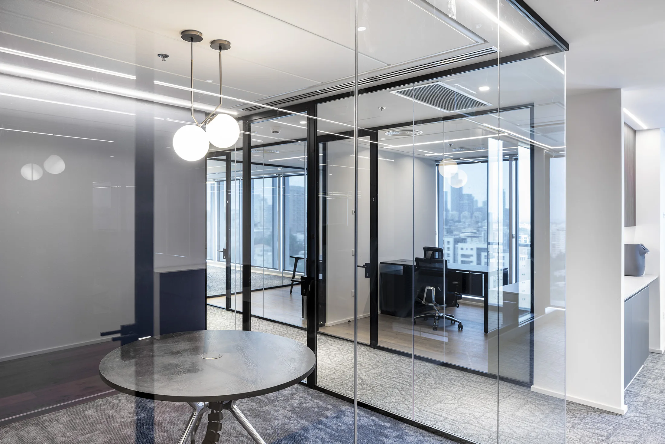 A seating nook with globe pendants and a glazed office with a view