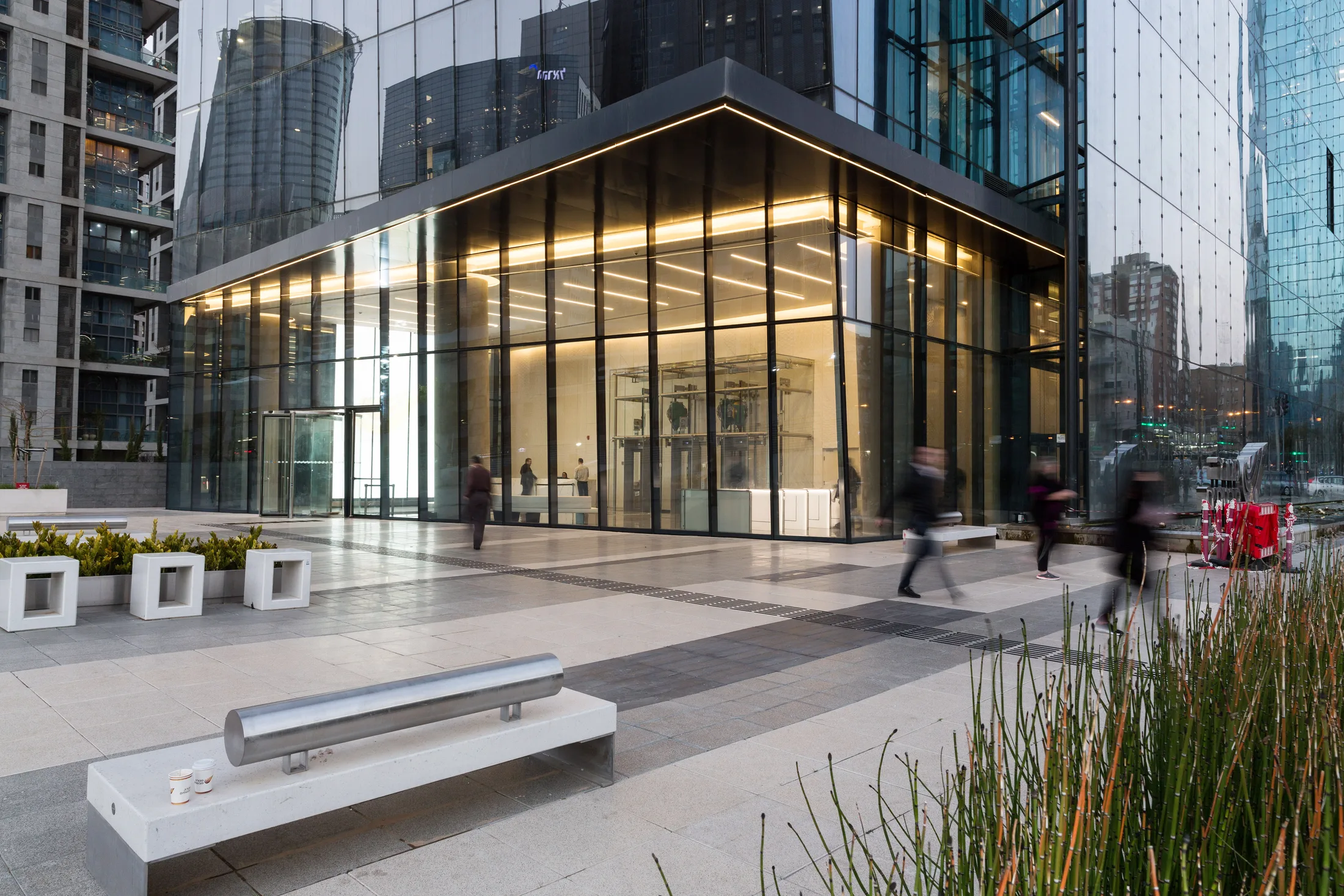 The illuminated glass lobby and entrance plaza at dusk