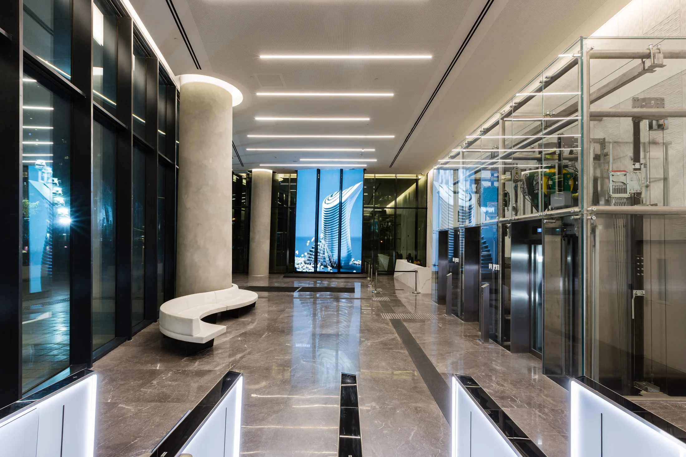 The main lobby with a stone column, bench, and linear lighting