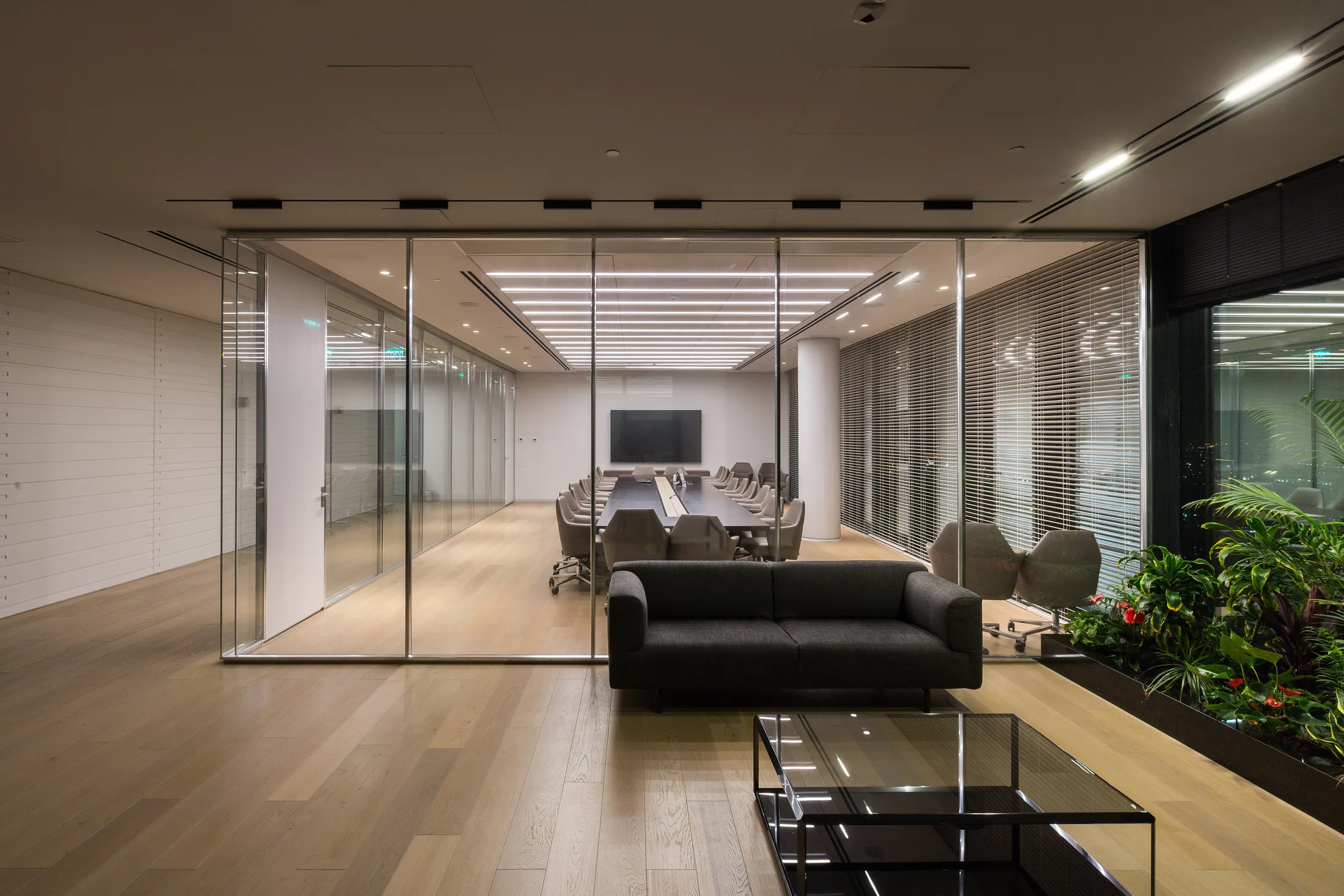 An executive lounge beside a glazed meeting room at night