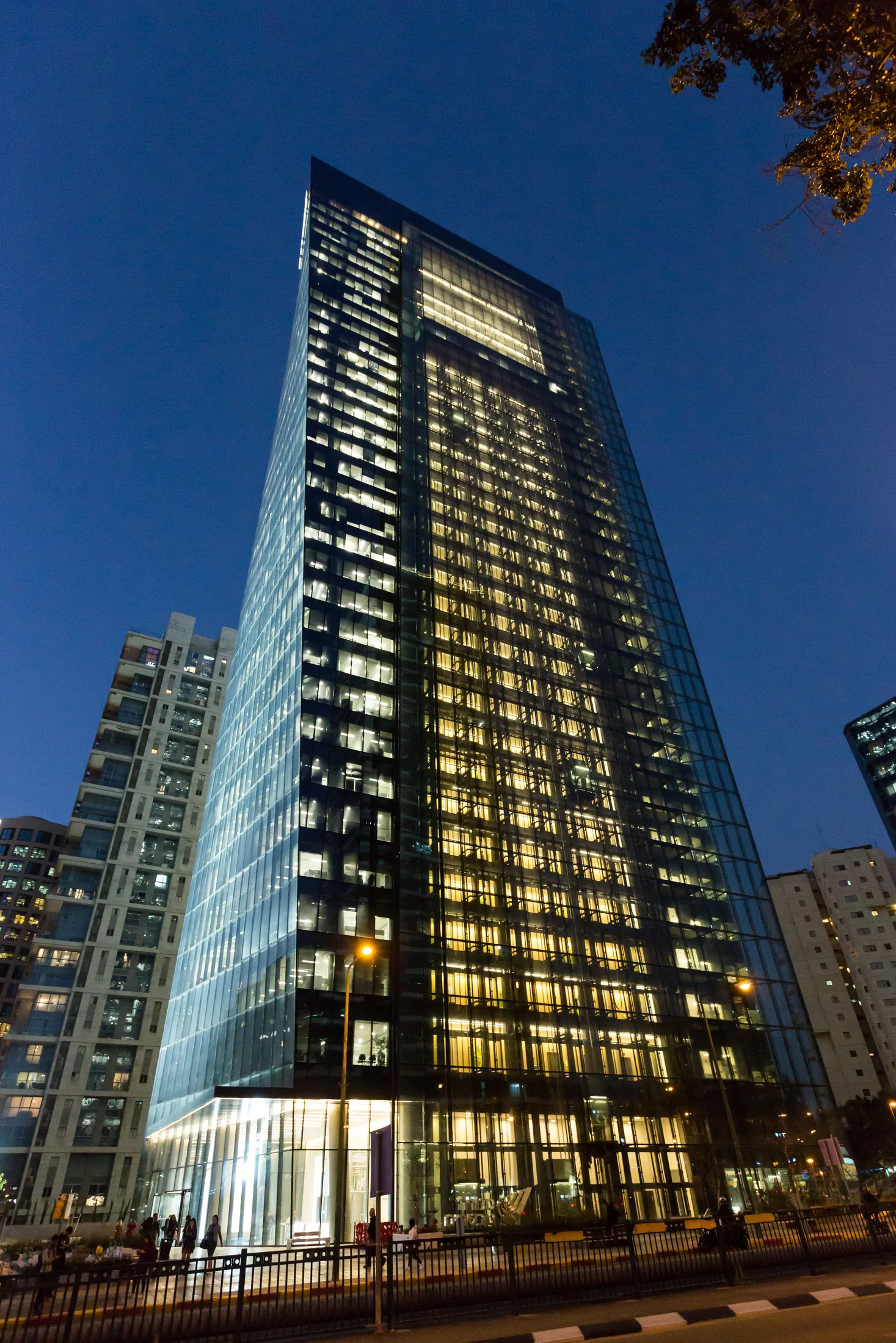 The tower at night with a glowing glass curtain wall