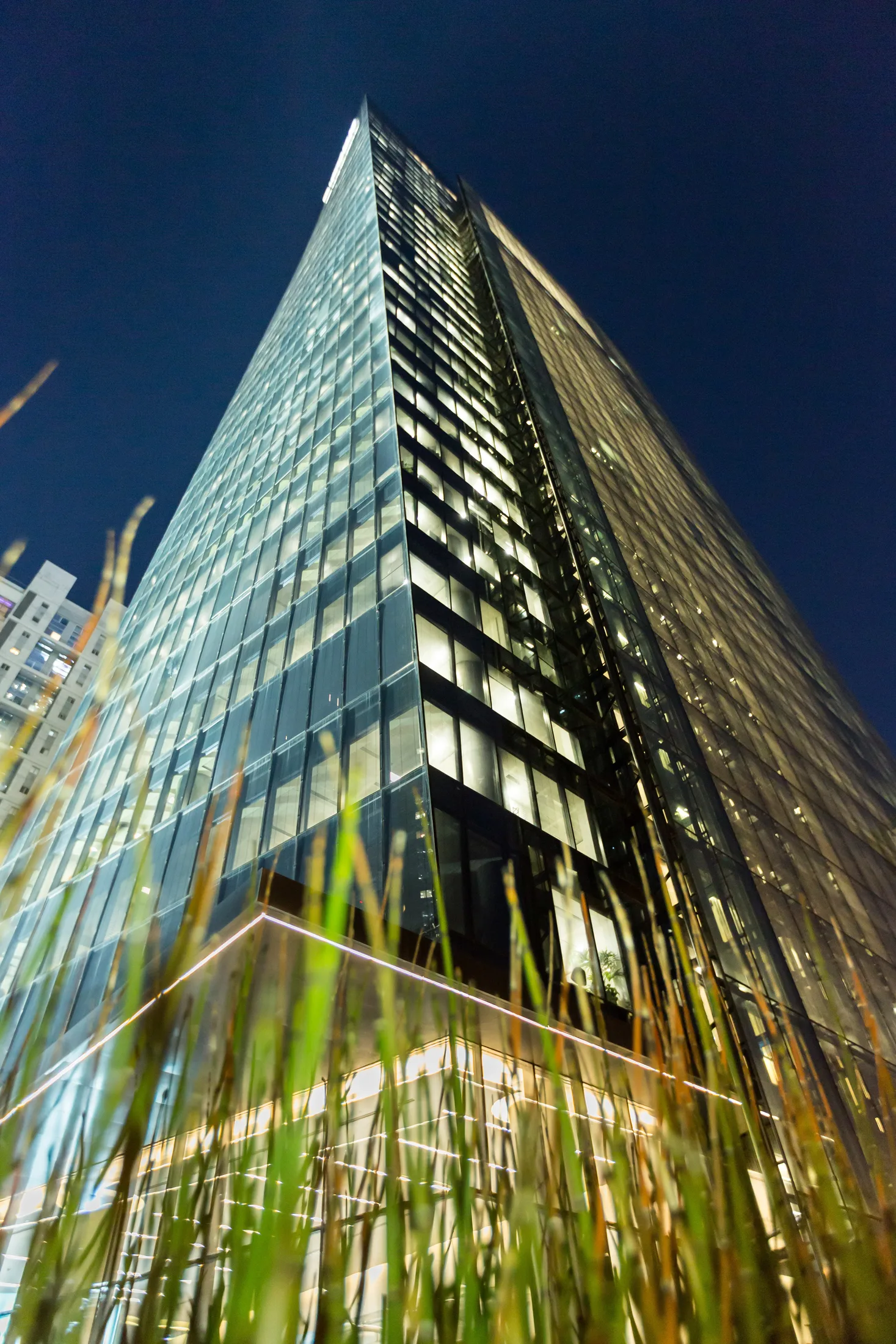 An upward view of the tower's glass corner at night