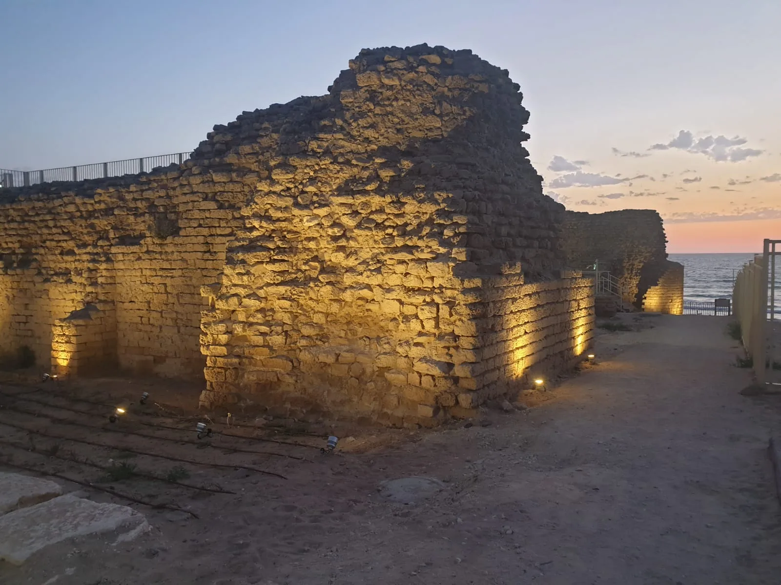 Fortress wall uplit at sunset above the Mediterranean