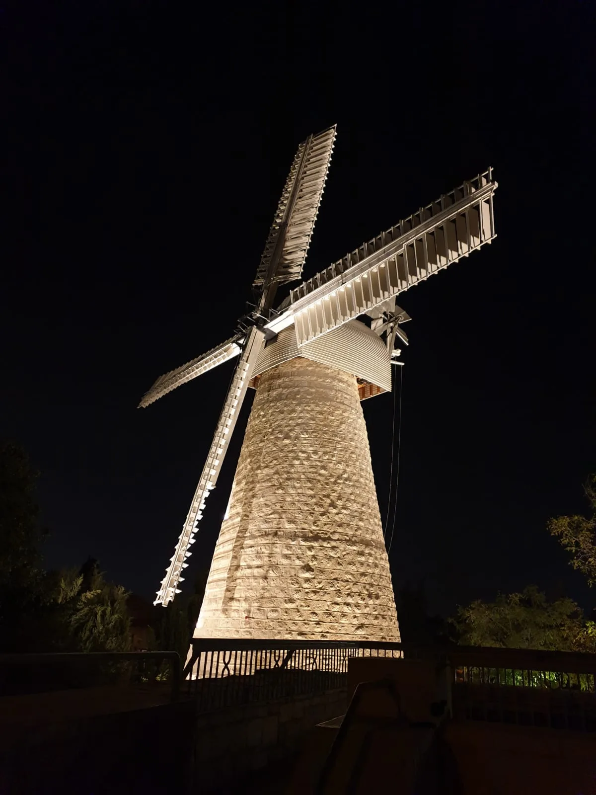 Stone tower and windmill sails in night lighting