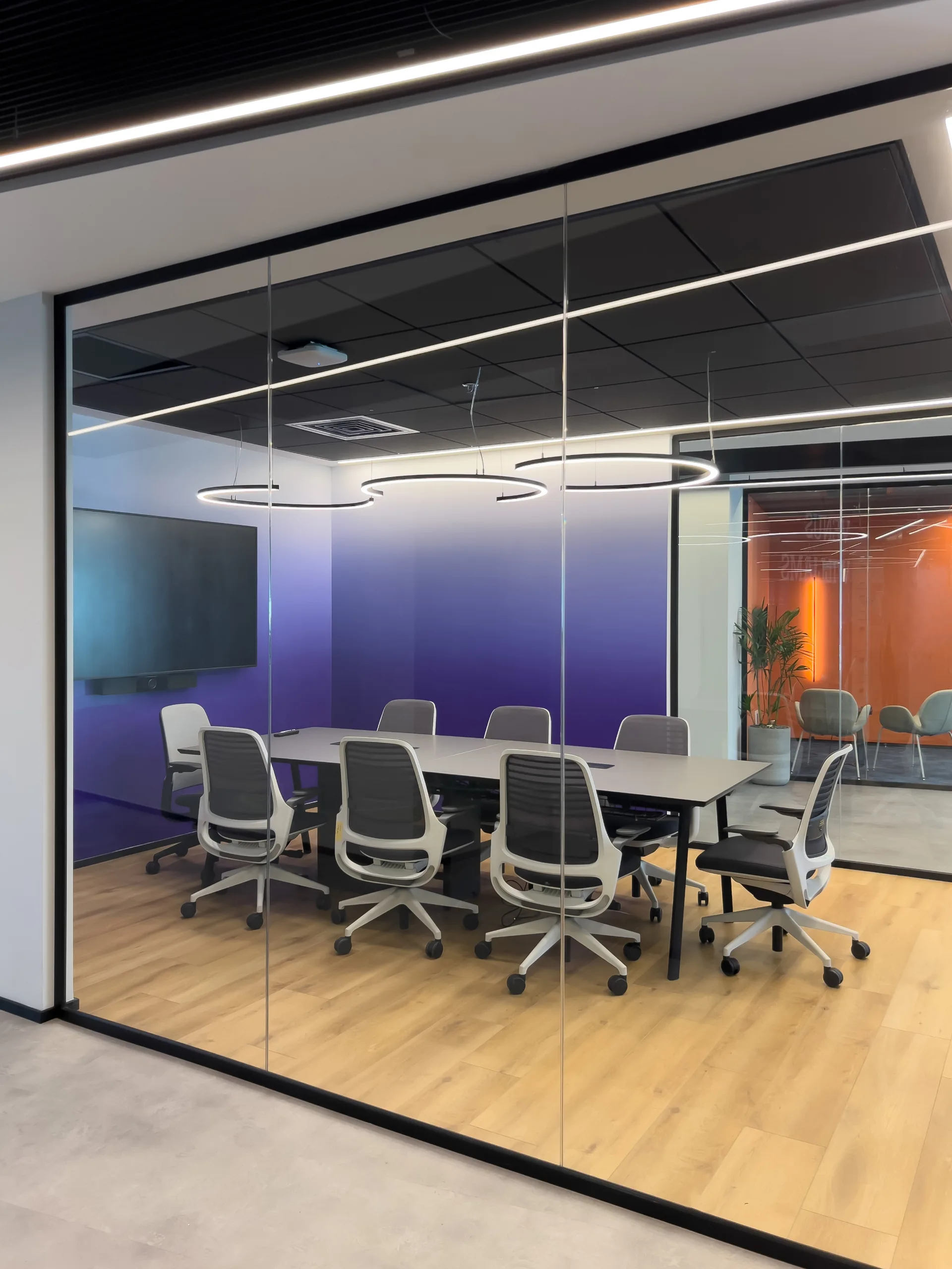 Glazed meeting room with a purple gradient wall and light rings