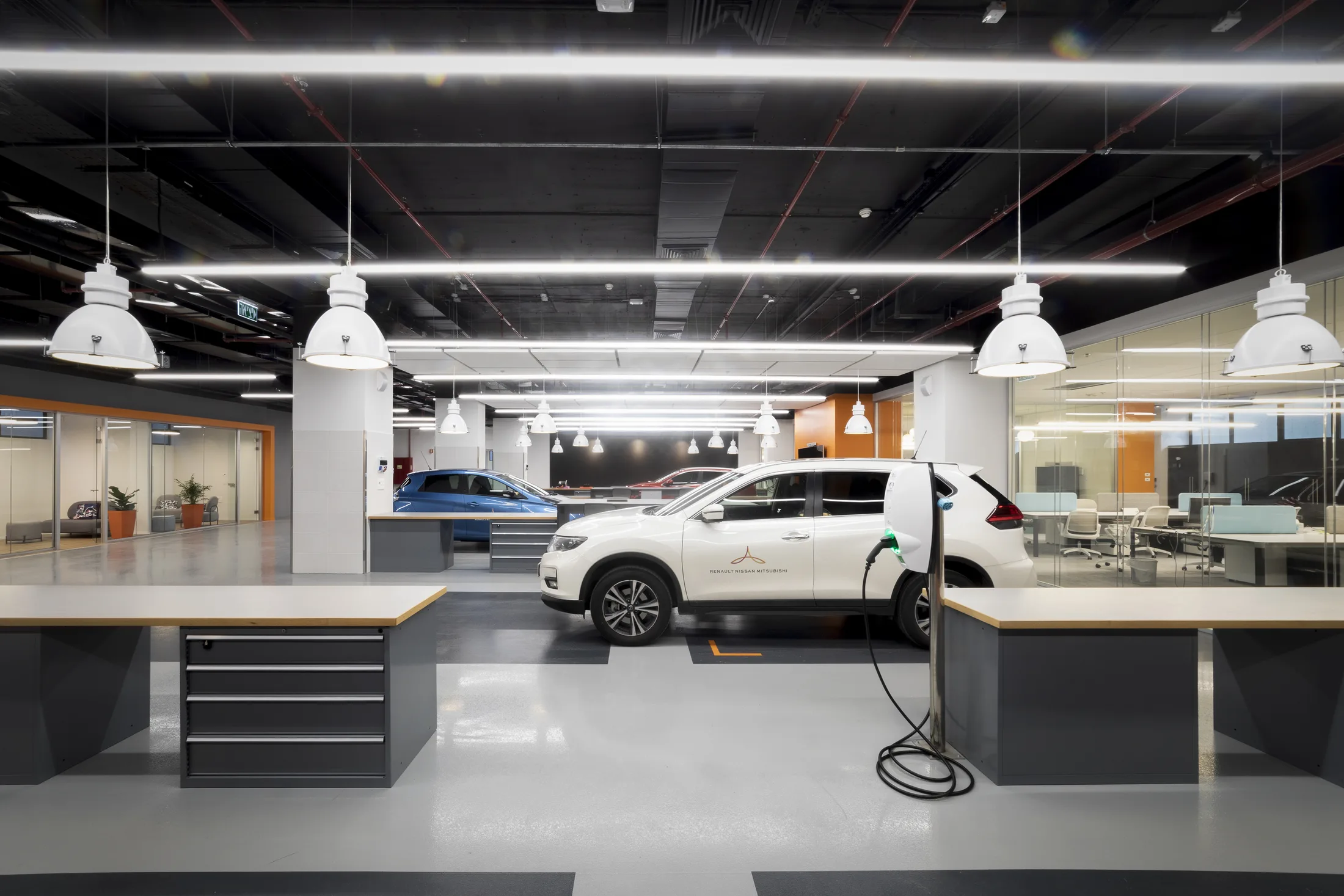 An electric vehicle charging in the lab beneath linear lighting