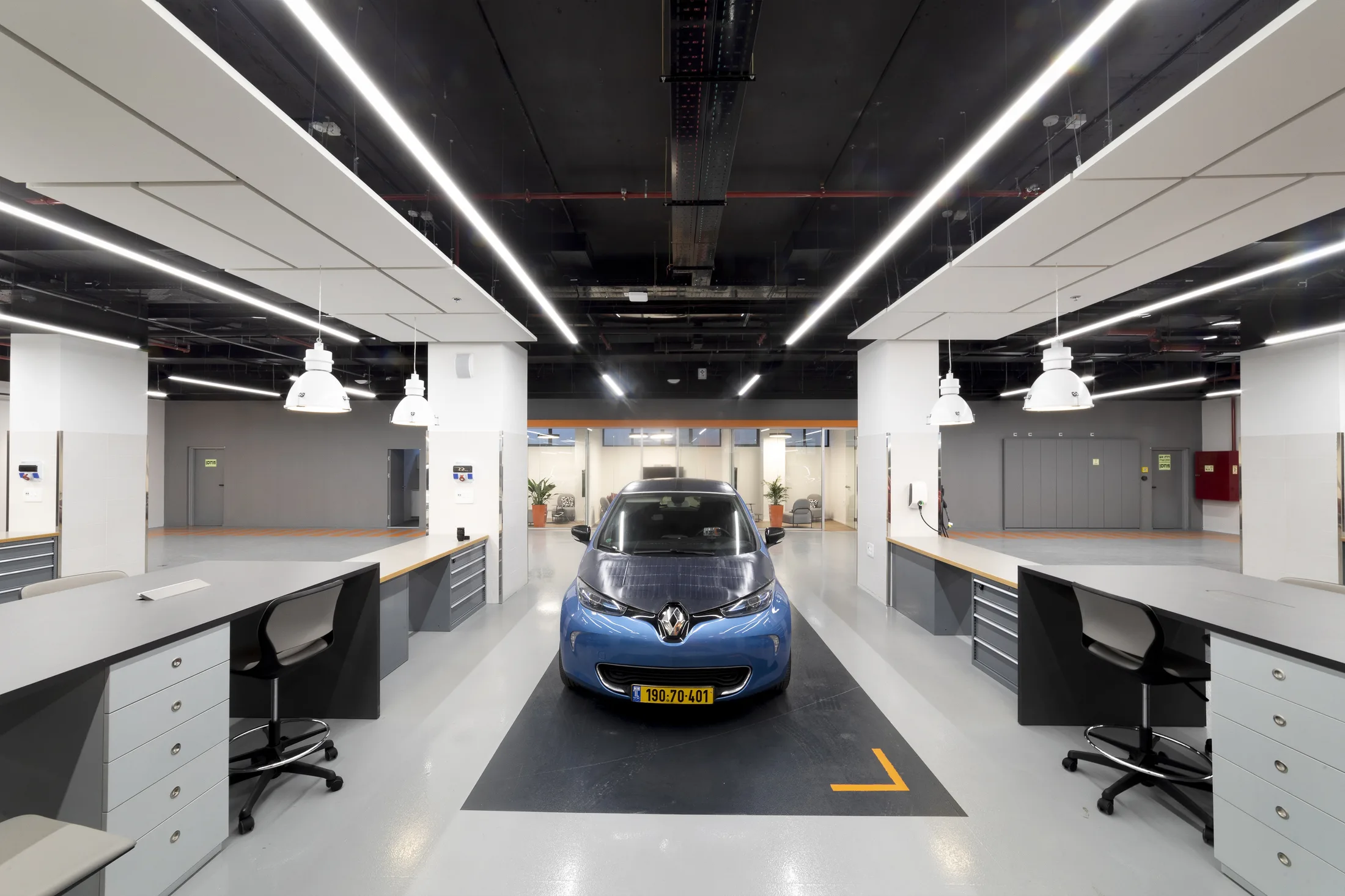 A test vehicle centered between workbenches under linear light