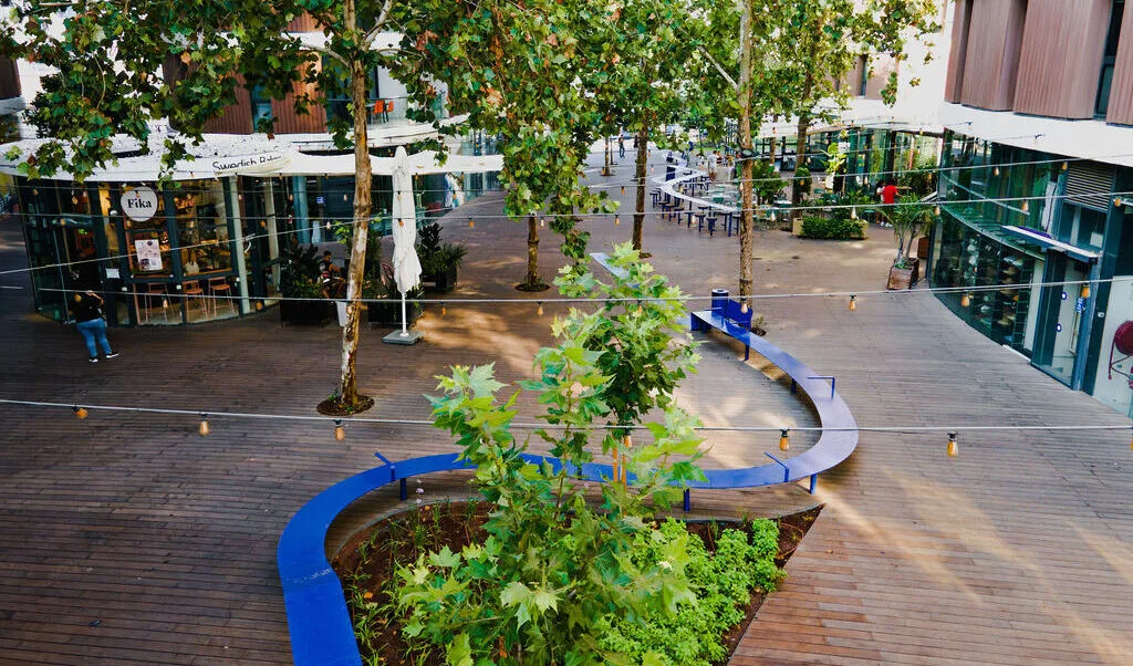 Central plaza with curved seating, planting, and cafés
