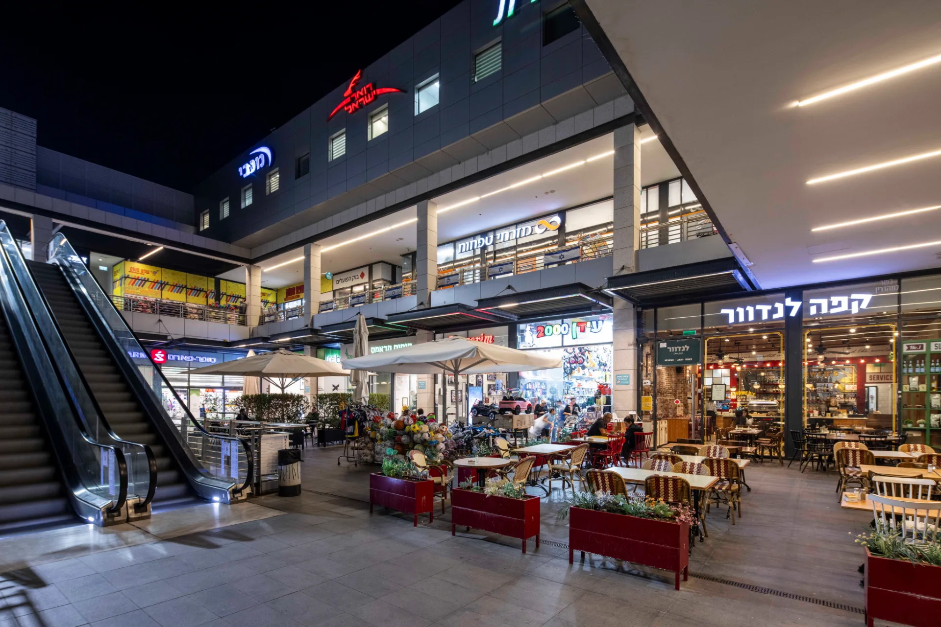 Retail arcade and escalator under linear ceiling lighting