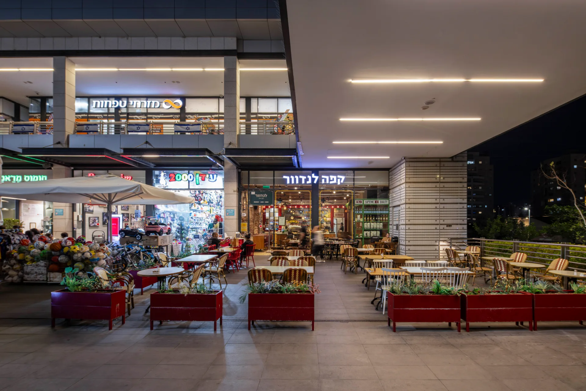 Storefronts and cafe seating along the arcade at night